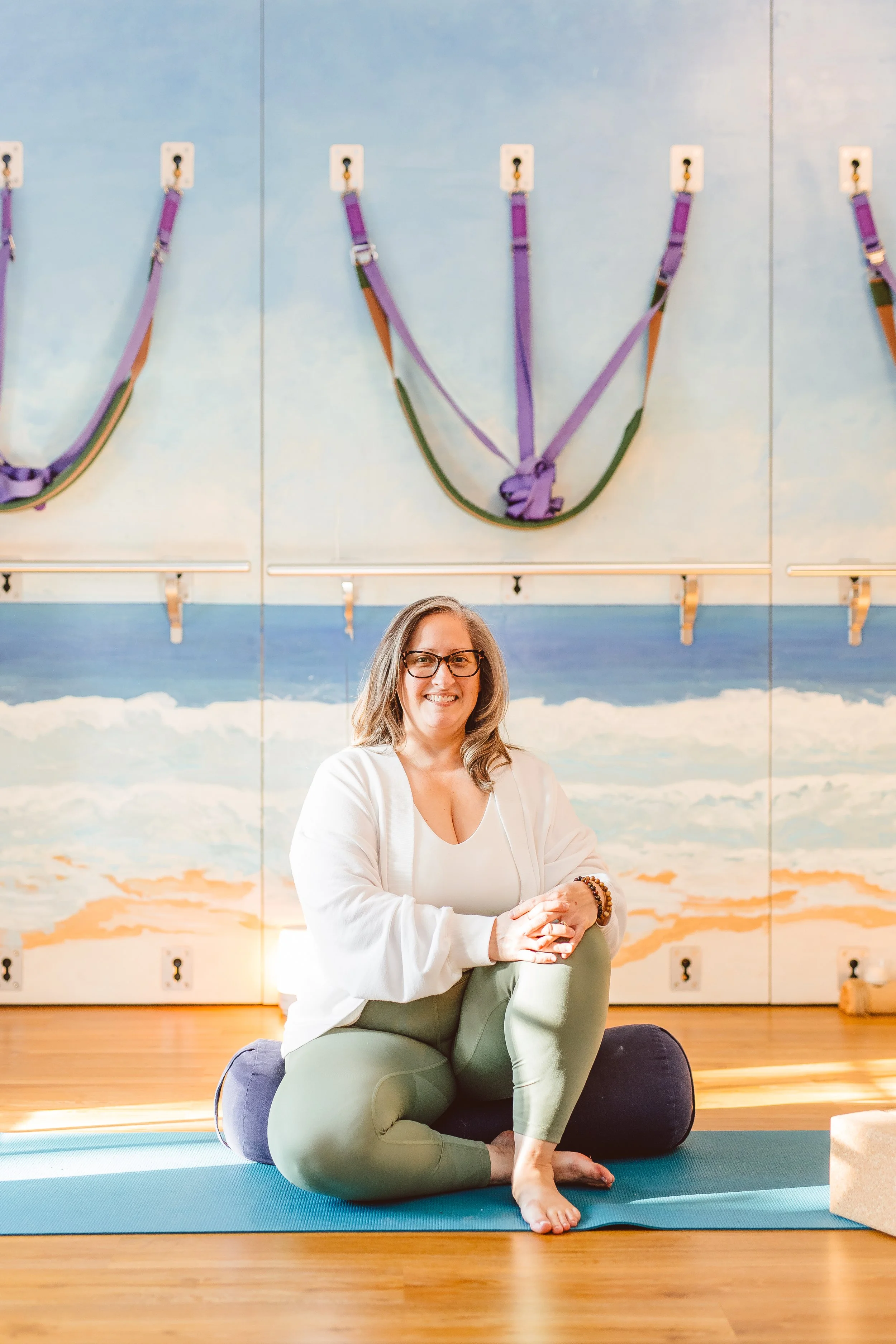 Happy client seated on a yoga mat at Coastal Retreat Studios in Easton, MD — somatic yoga and Pilates classes that help you build a body you can trust