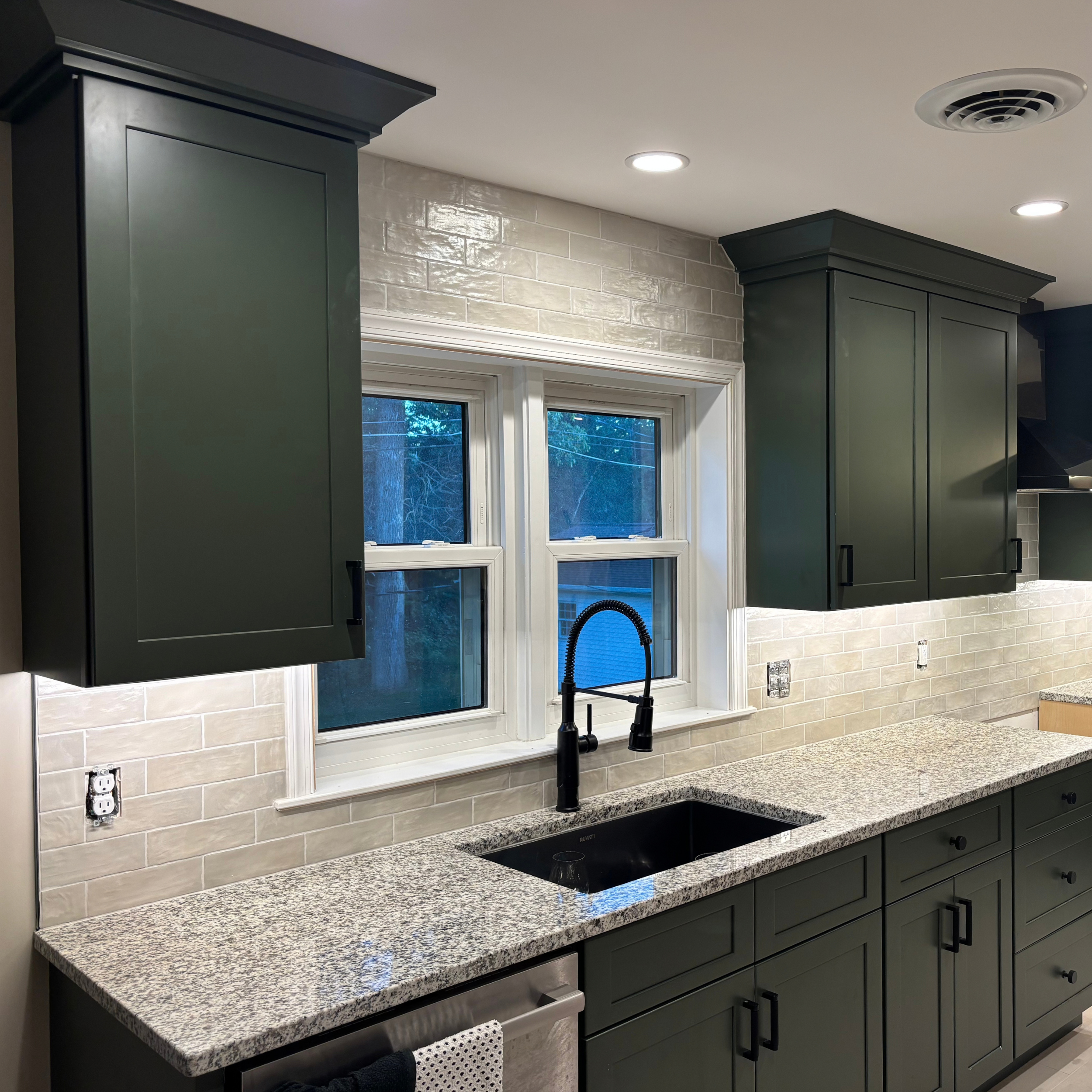 Green cabinetry with complimentary sage colored tiles.