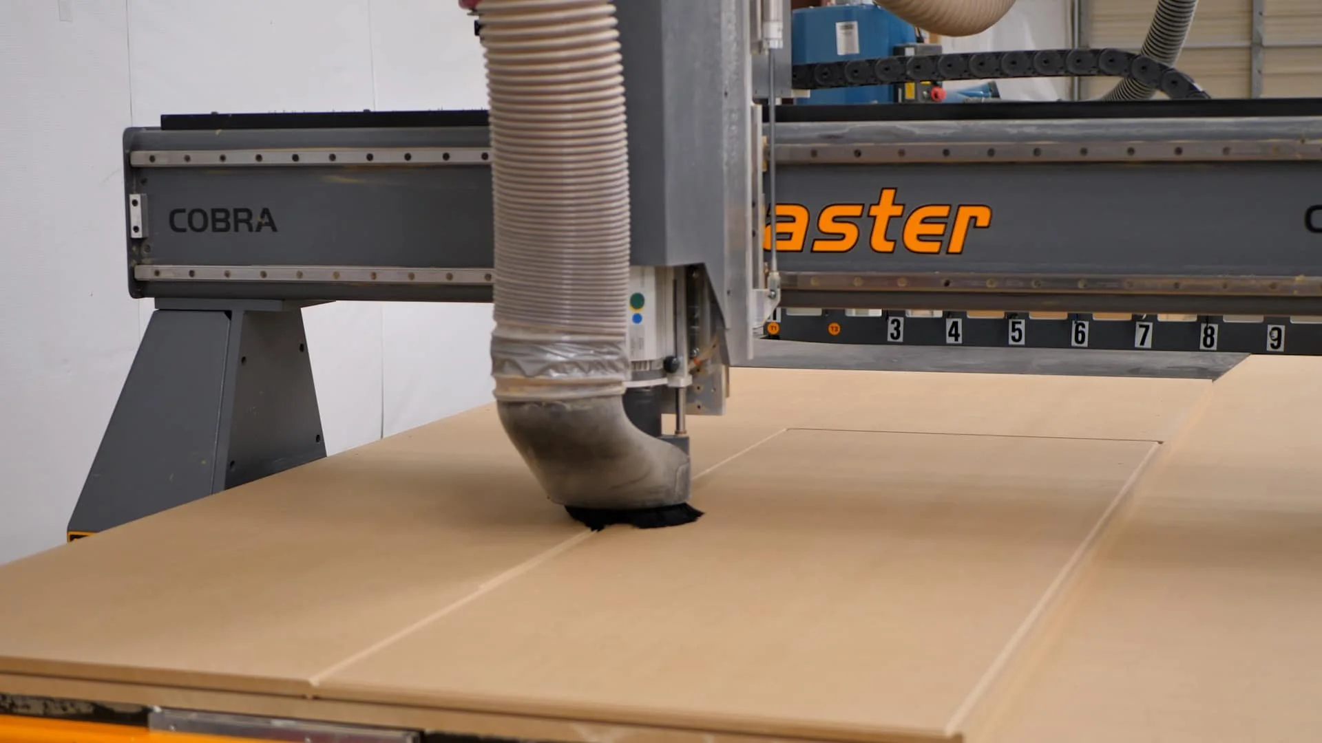 Industrial CNC router machine cutting plywood sheets in a workshop.
