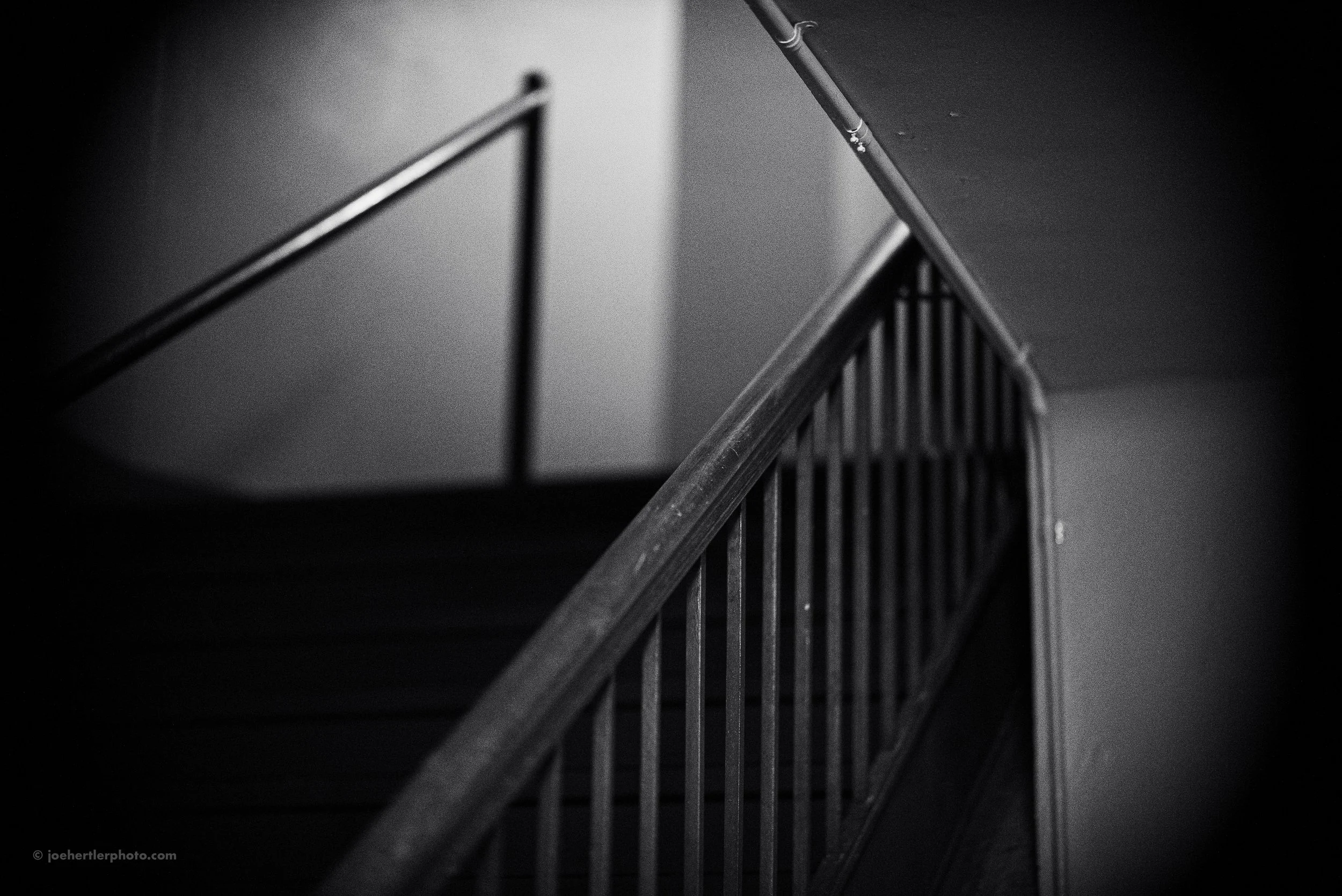 Black and white photo of a staircase with metal handrails and vertical bars.