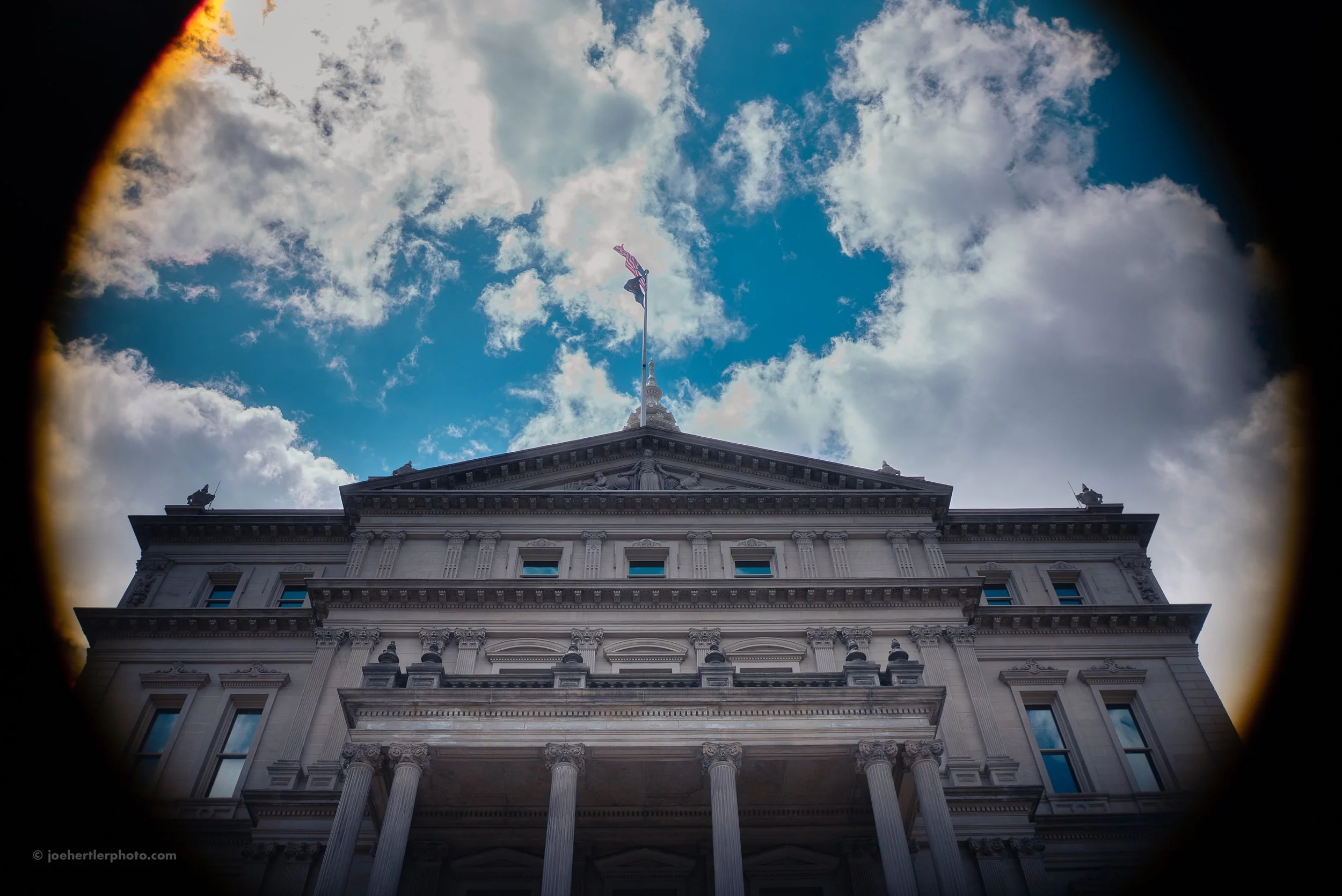 Looking up at the historic Capitol building with a cloudy sky in the background.