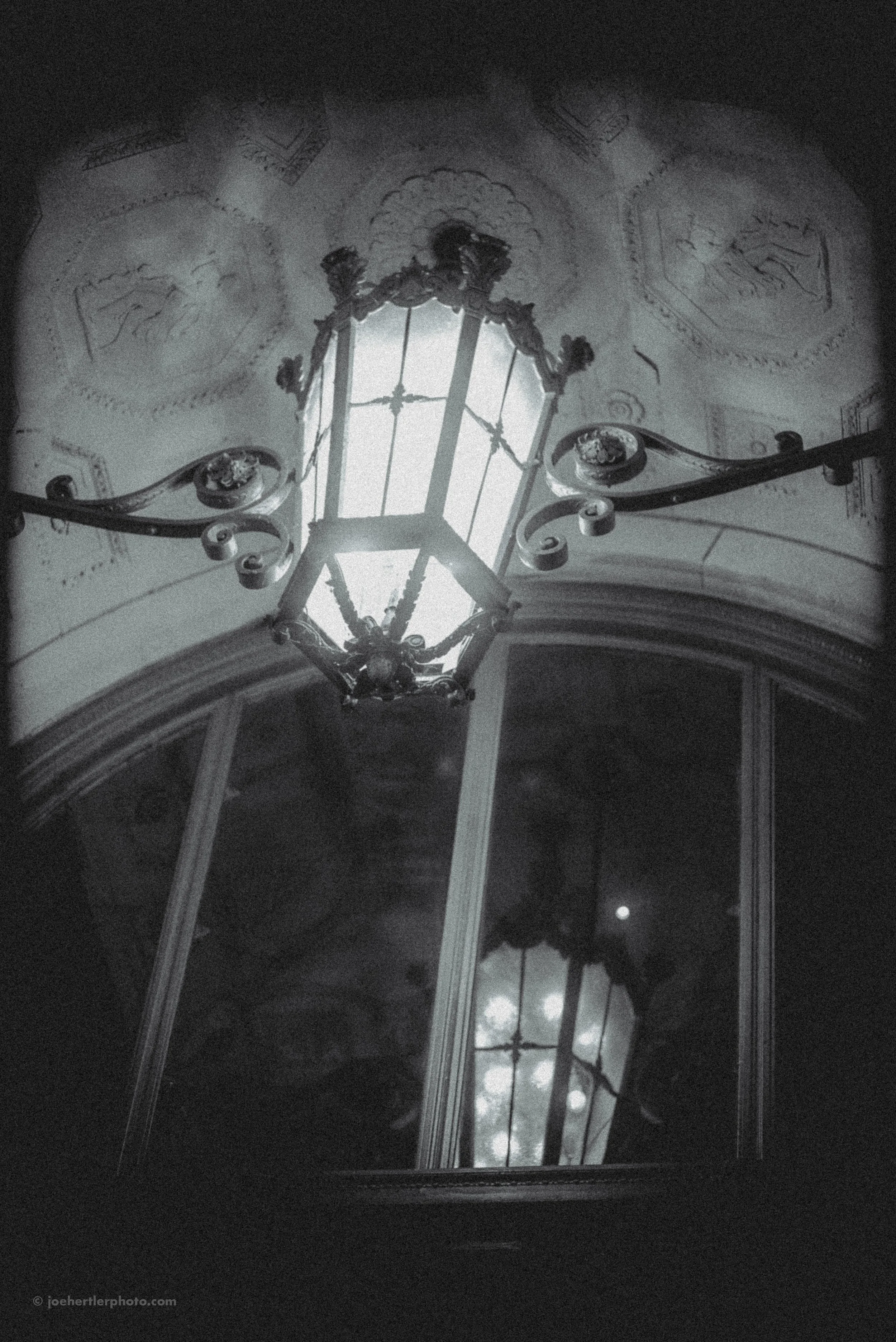 Reflection of a skylight and chandelier in a mirror on a ceiling in black and white.