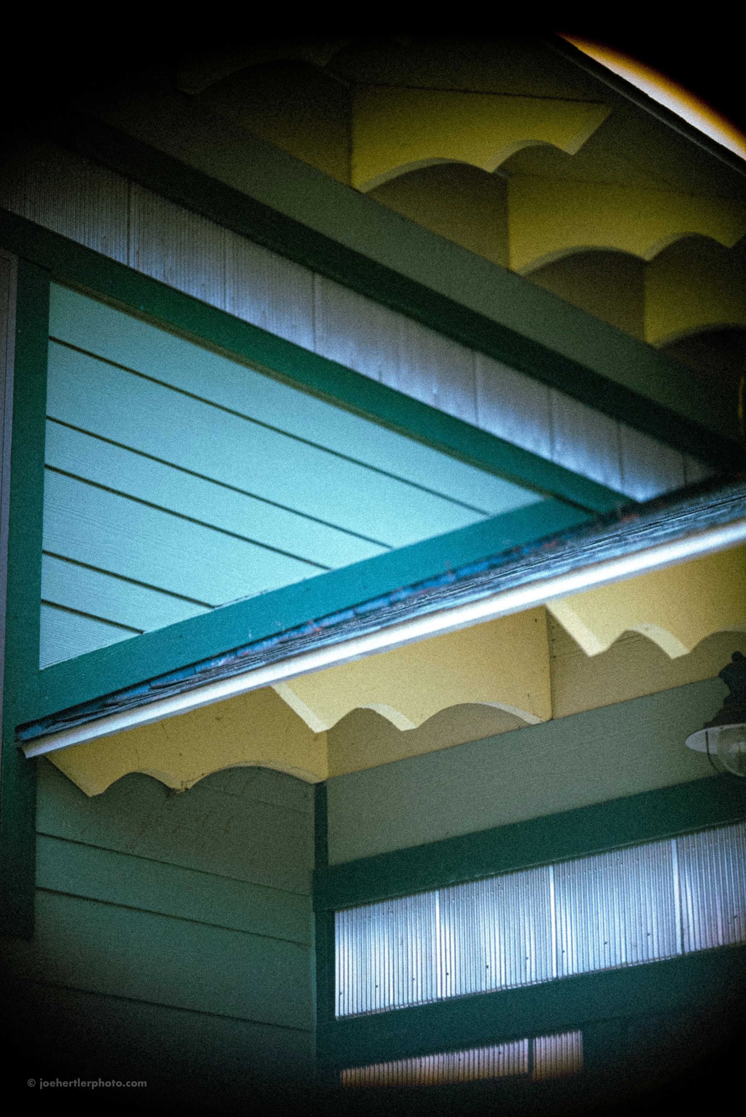 Close-up of stacked building awnings with green framing, beige scalloped valance, and frosted window panes.