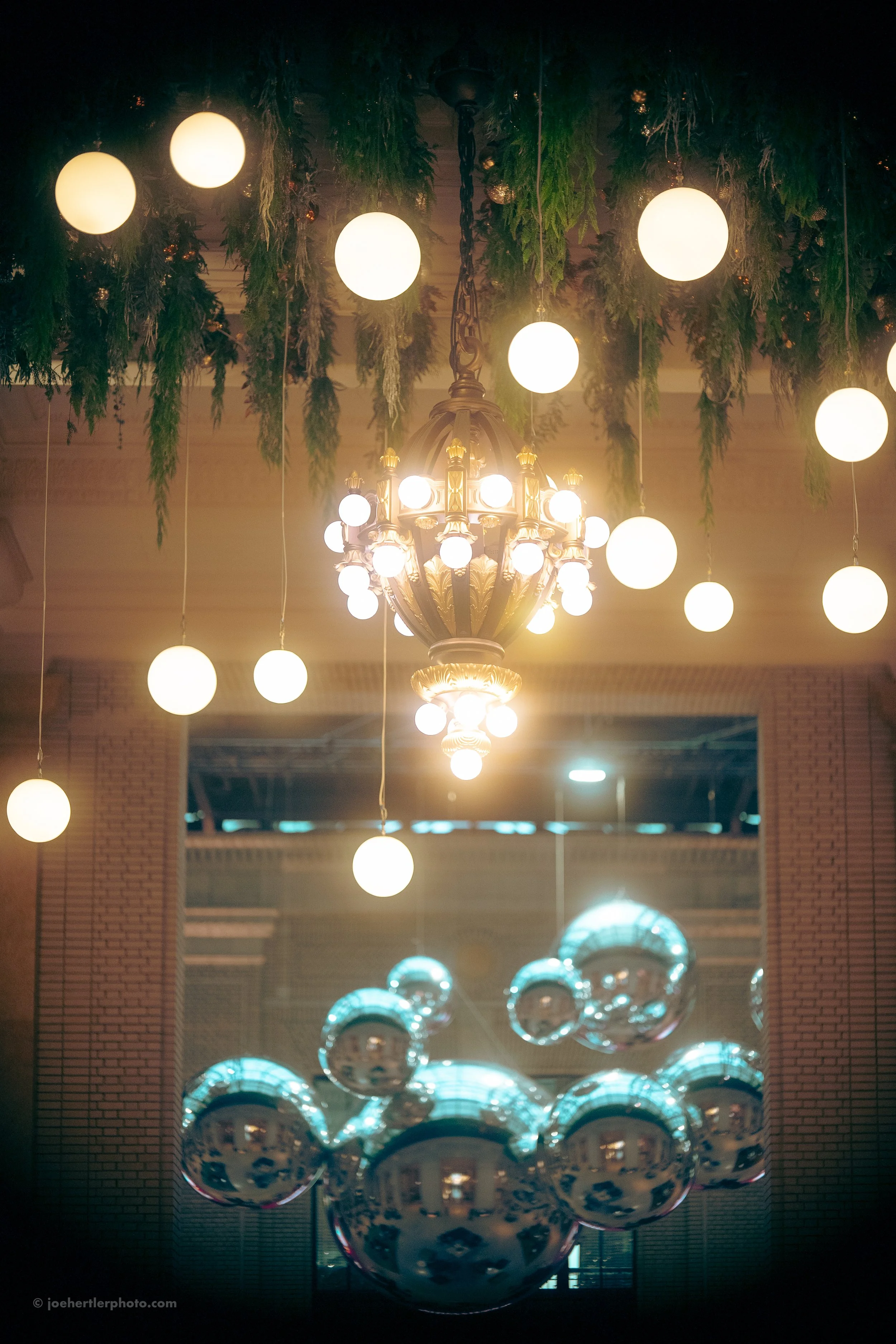 Decorative hanging lights and reflective silver spheres in a modern interior space.