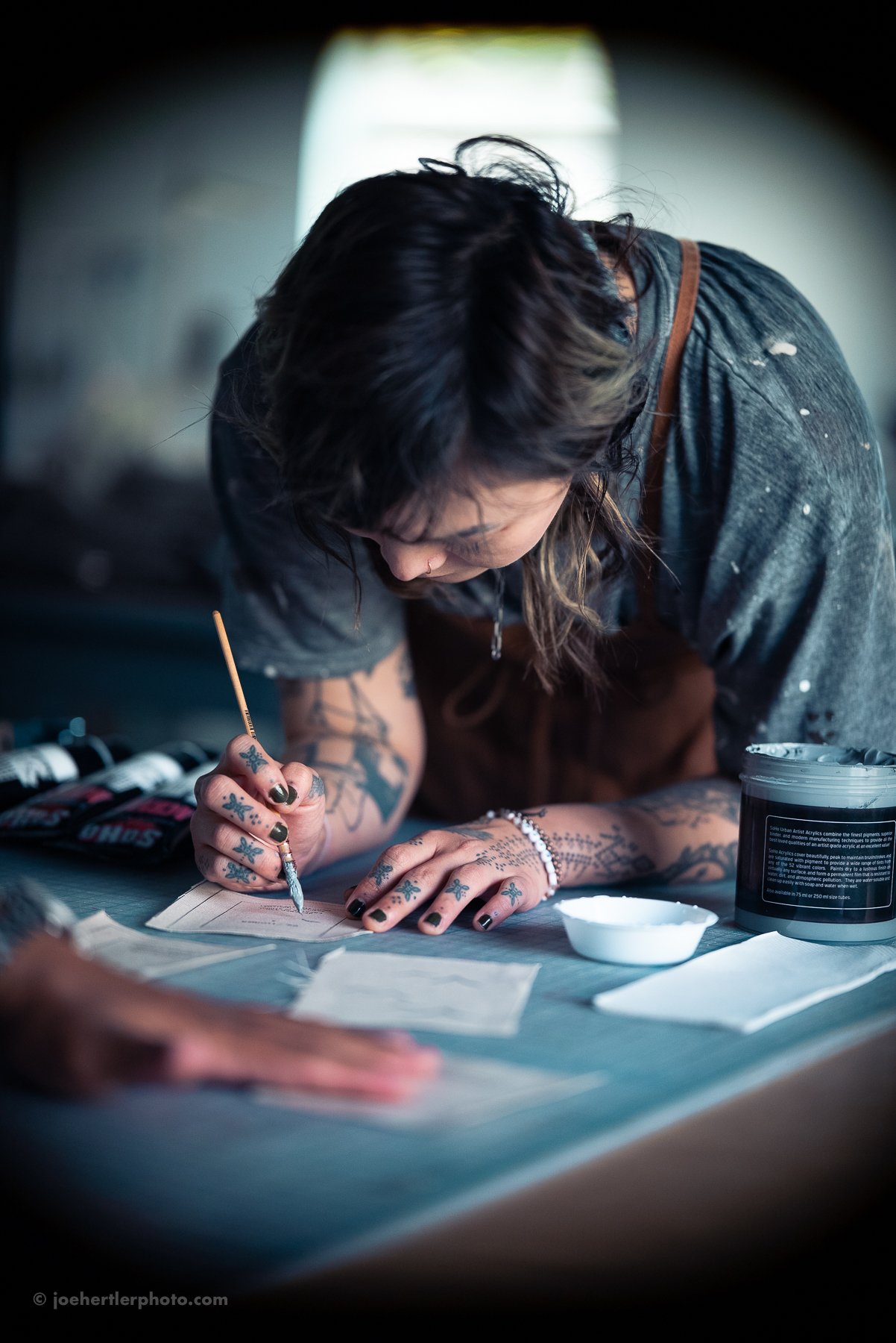 Tattoo artist creating a tattoo with ink and needle on a client's arm, surrounded by tattoo supplies.