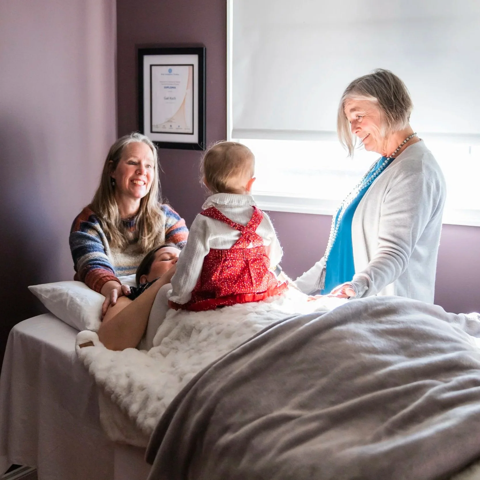 Two gentle practitioners working with a mother and baby towards bonding and relationship development.