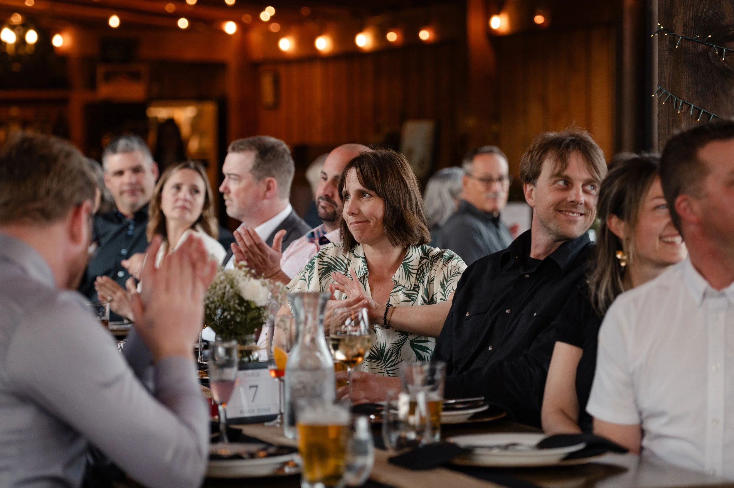 People seated at Feed the Valley 2025, engaging in conversation, with floral centerpieces and drinks.