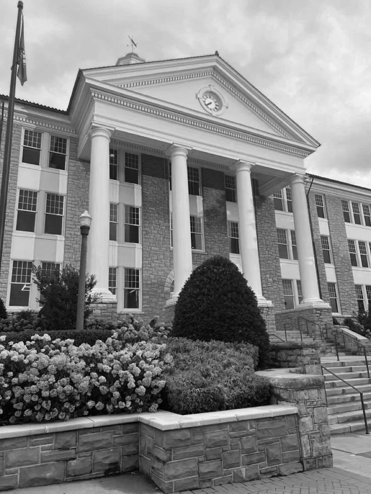 A historic building with classical architecture featuring large columns, a clock, and a triangular pediment.