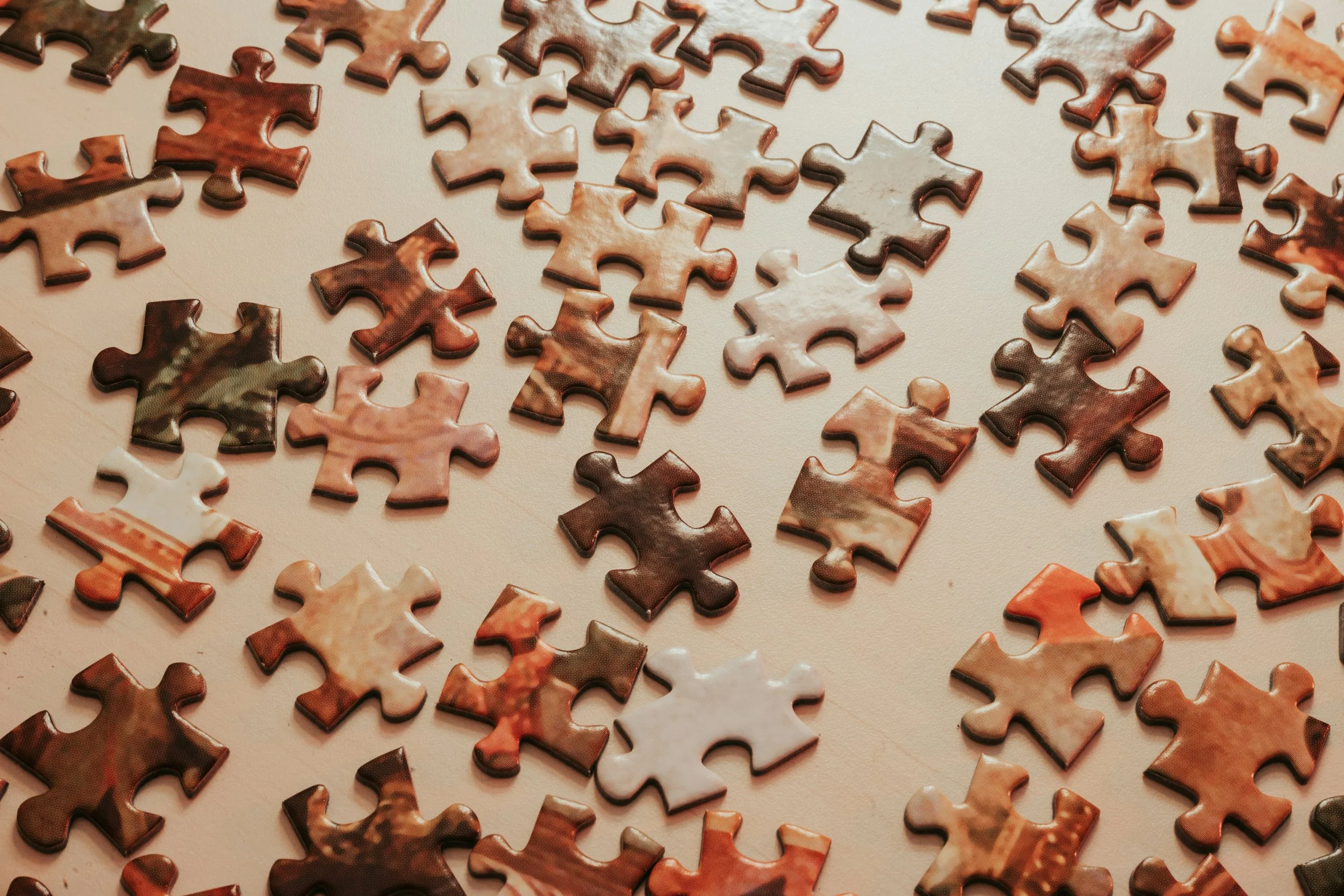 Scattered multicolored jigsaw puzzle pieces on a light surface.