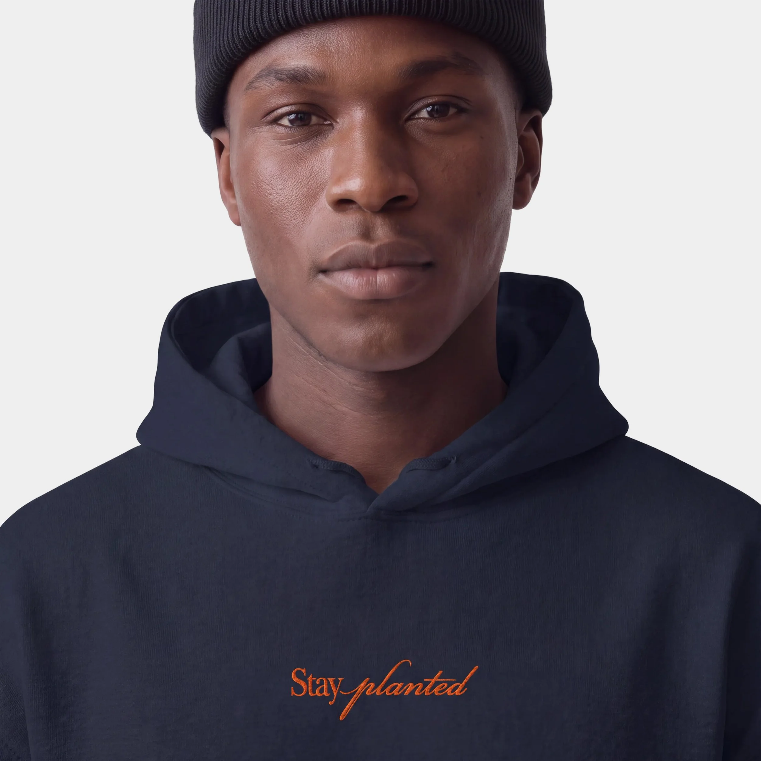 Model wearing the Fruit & Form Stay Planted black hoodie with orange embroidery.