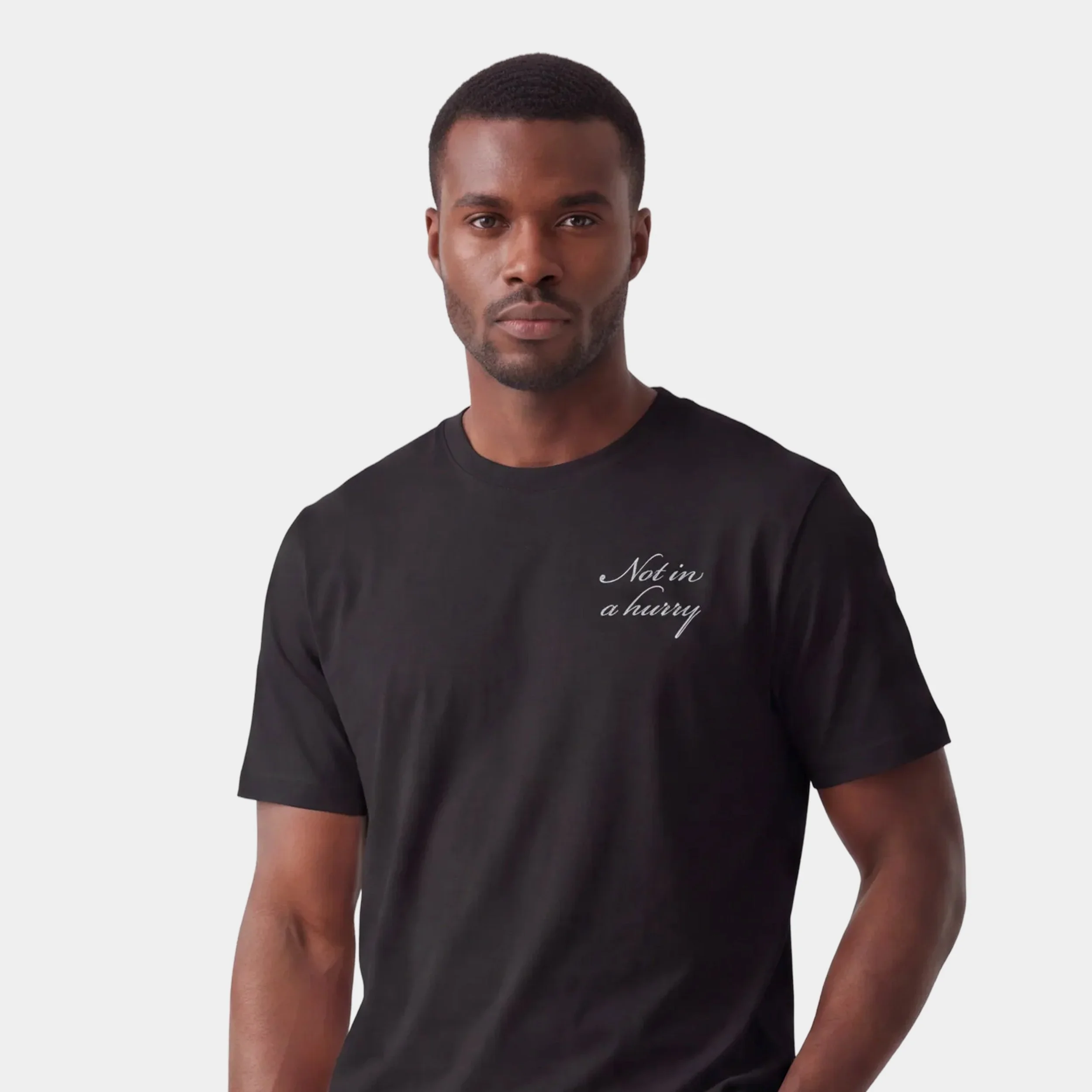 Model wearing the Fruit & Form Not in a Hurry black T-shirt with light gray script.