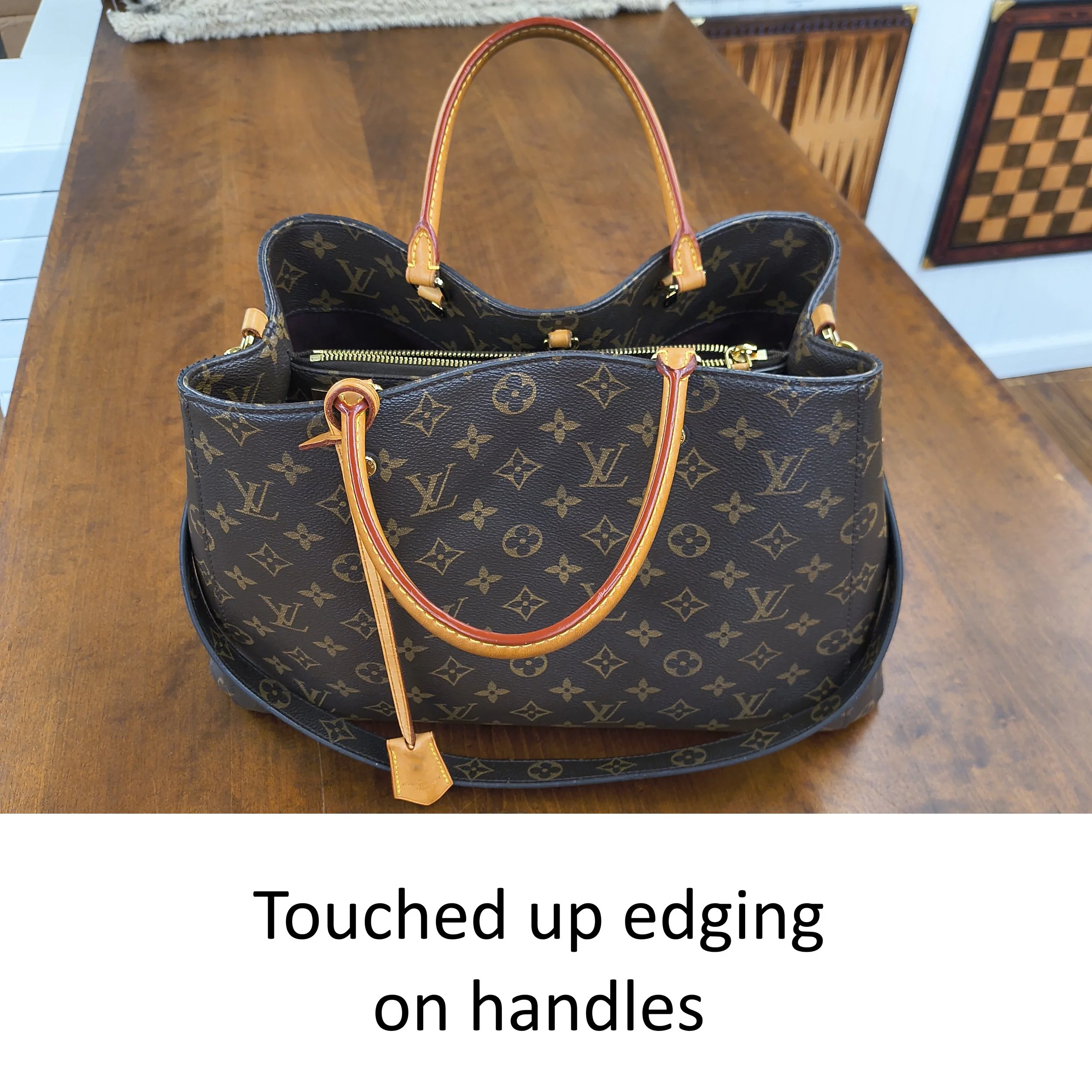 A Louis Vuitton tote bag placed on a wooden table with a background of decorative wall art.