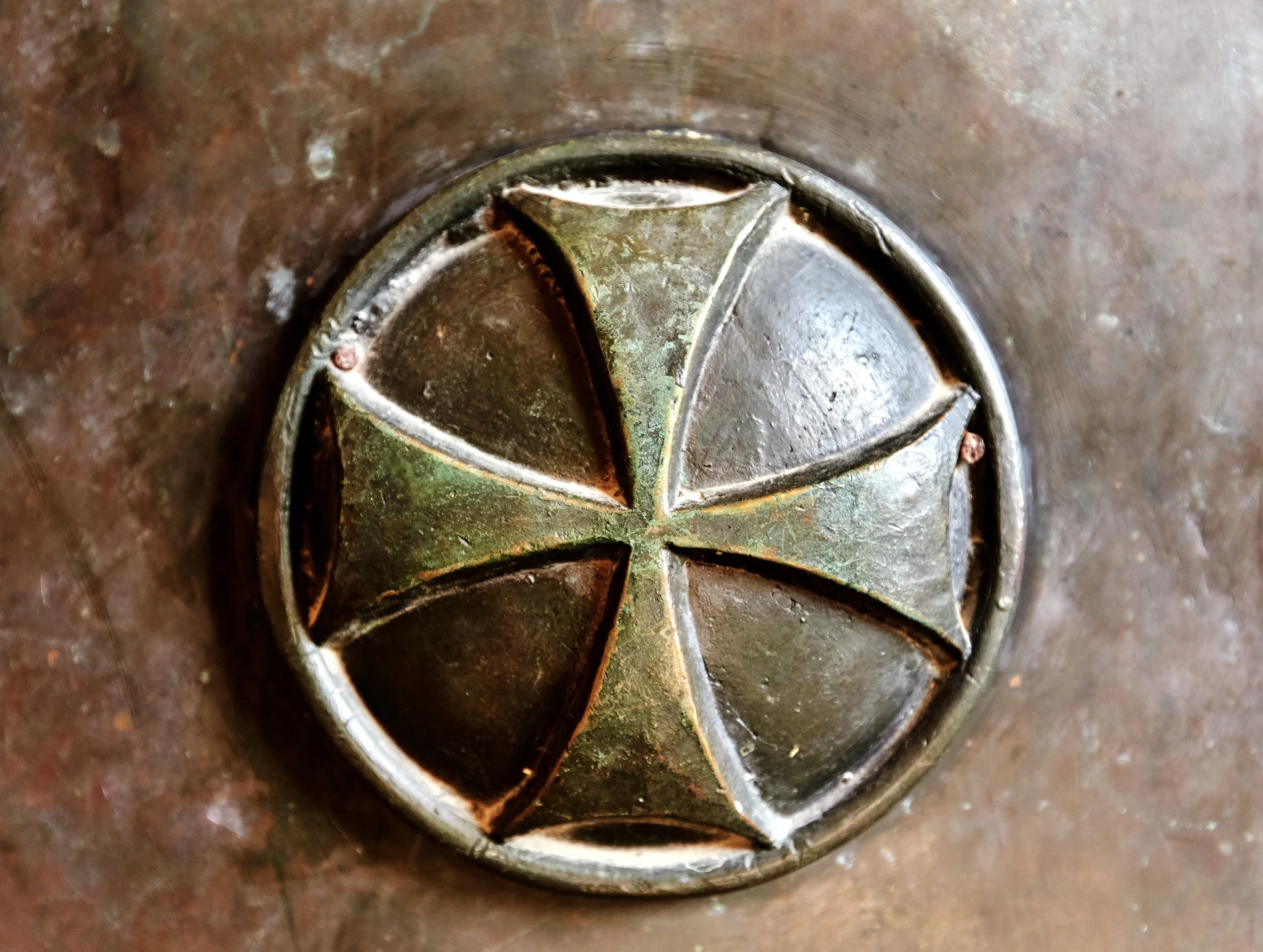 Close-up of a metallic object that appears to be part of a wheel or gear, showing rust, corrosion, and a central hole.