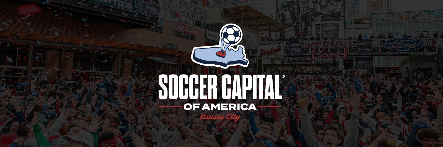 Crowd of people at a soccer game or event with a large banner and advertising signage in the background, and a logo with a soccer ball and snowshoe in the foreground.