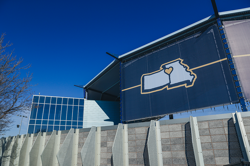 Large outdoor billboard featuring the outline of the state of North Carolina with a heart over the Piedmont region, on a modern building against a clear blue sky.