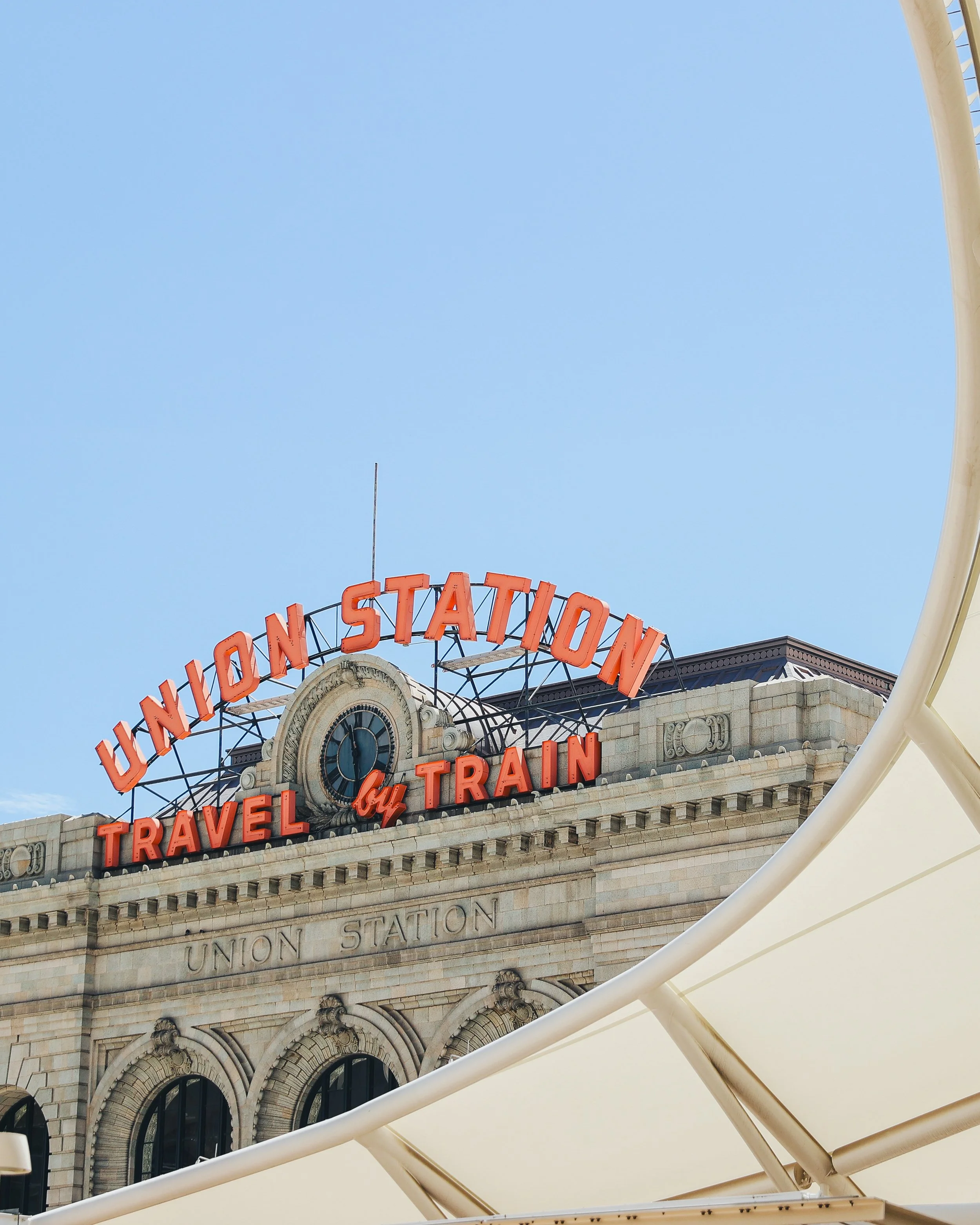 Sign for Union Station that reads 'Travel by Train' in bright orange letters