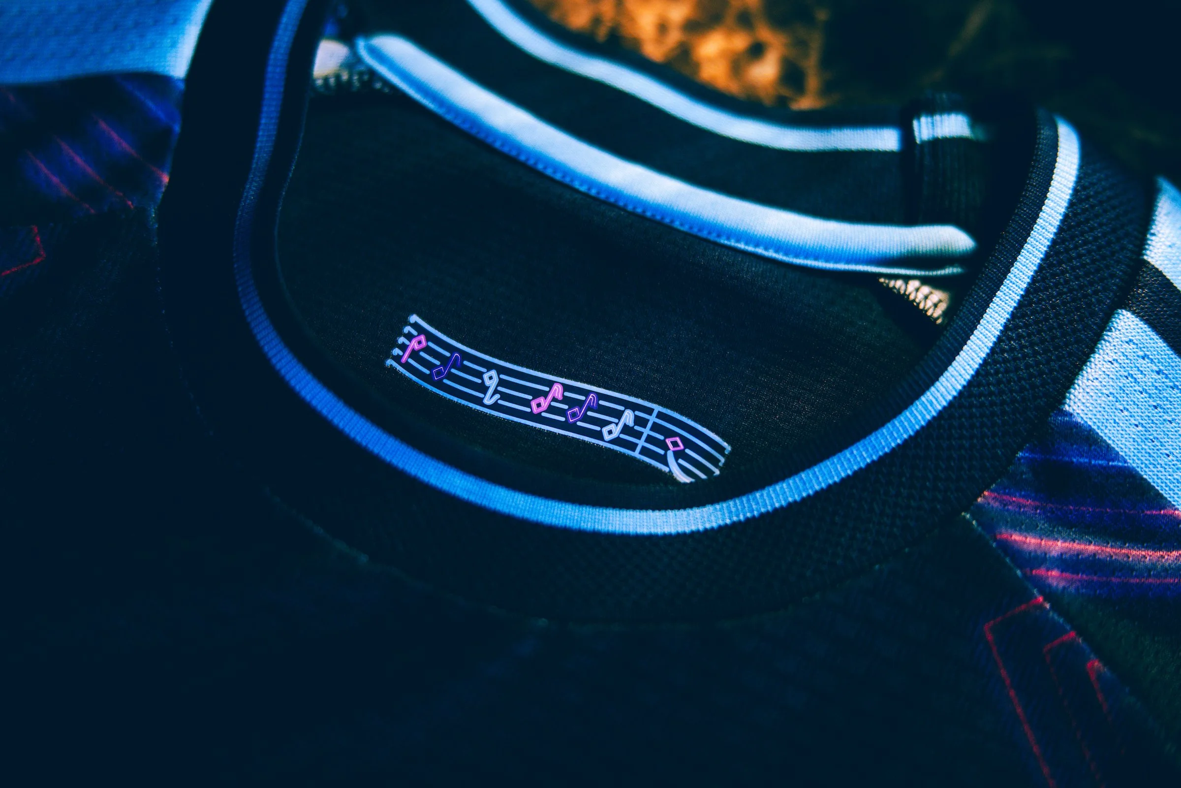 Close-up of a black bag with a musical note design on a pocket, showing blue and white accents.