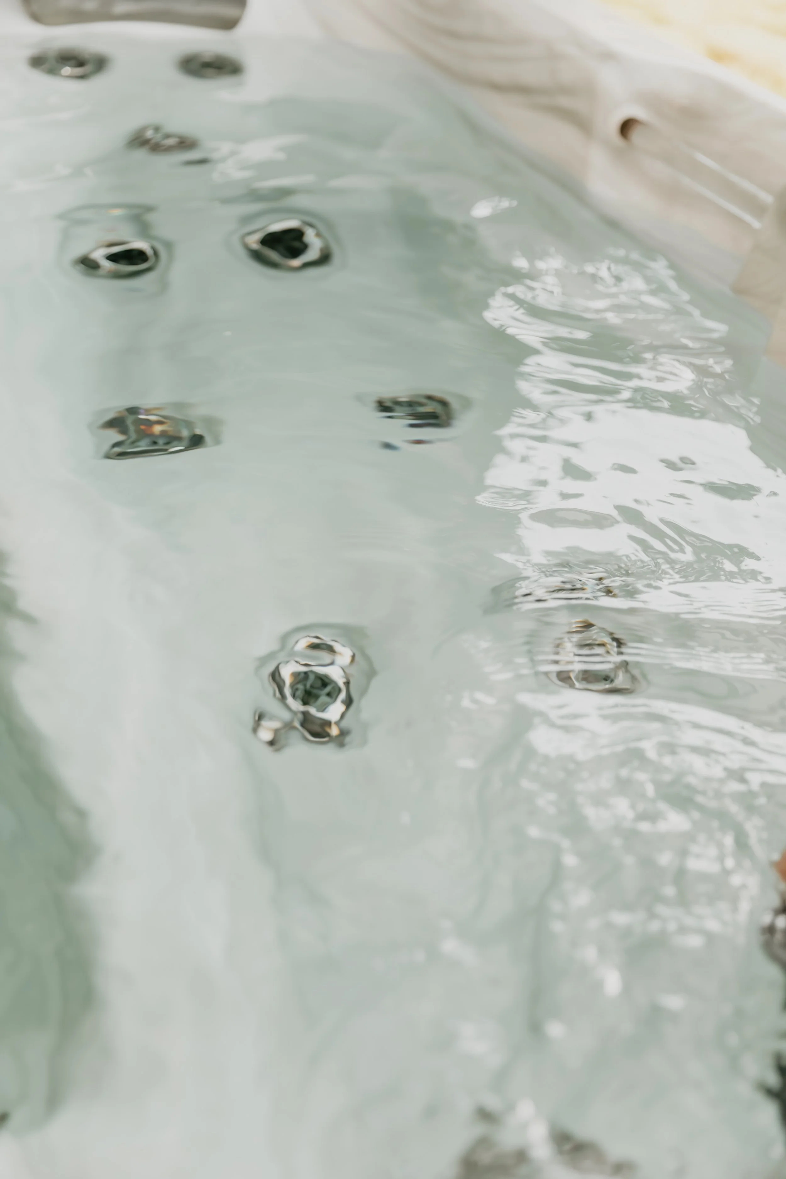 Close-up of hot tub jets in water with some bubbles and swirling water.
