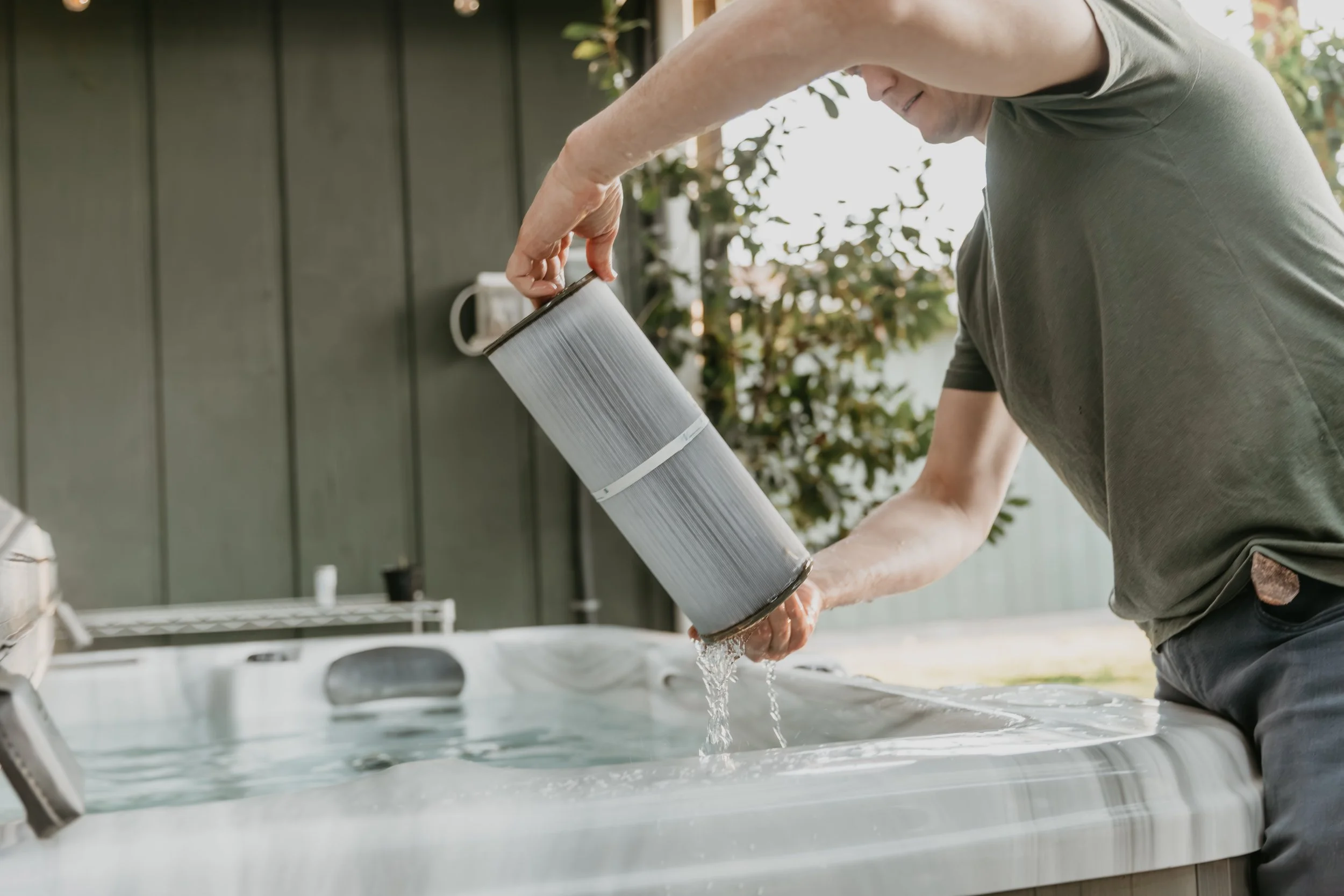 A person cleaning or replacing a filter in an outdoor hot tub or spa.