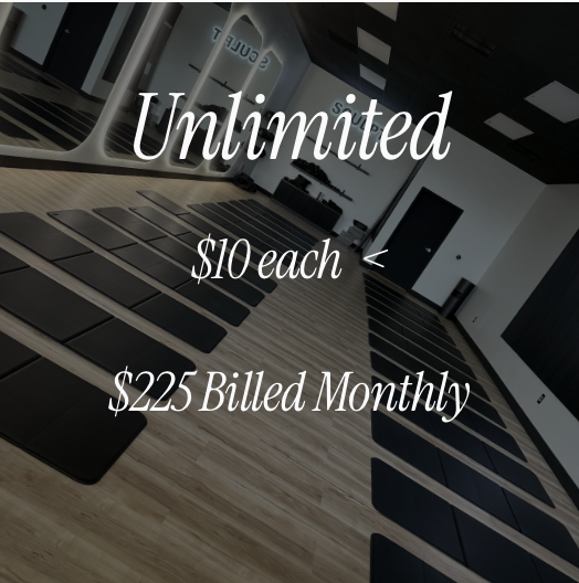 Interior of a fitness or yoga studio with black mats arranged on a wooden floor, large windows, and motivational text overlay about unlimited classes for $10 each billed monthly.