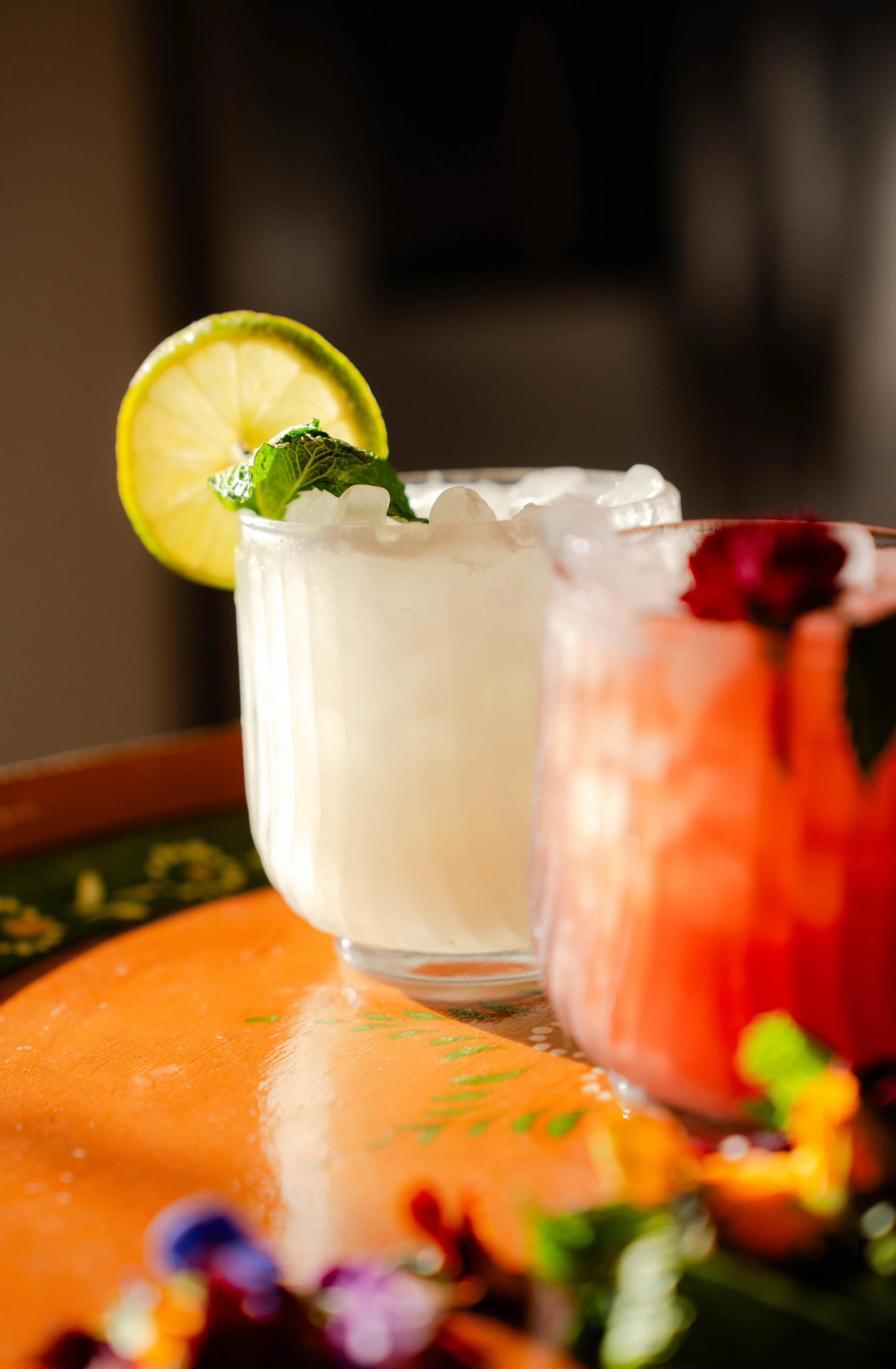 Colorful handcrafted cocktails garnished with fresh lime, mint, and edible flowers