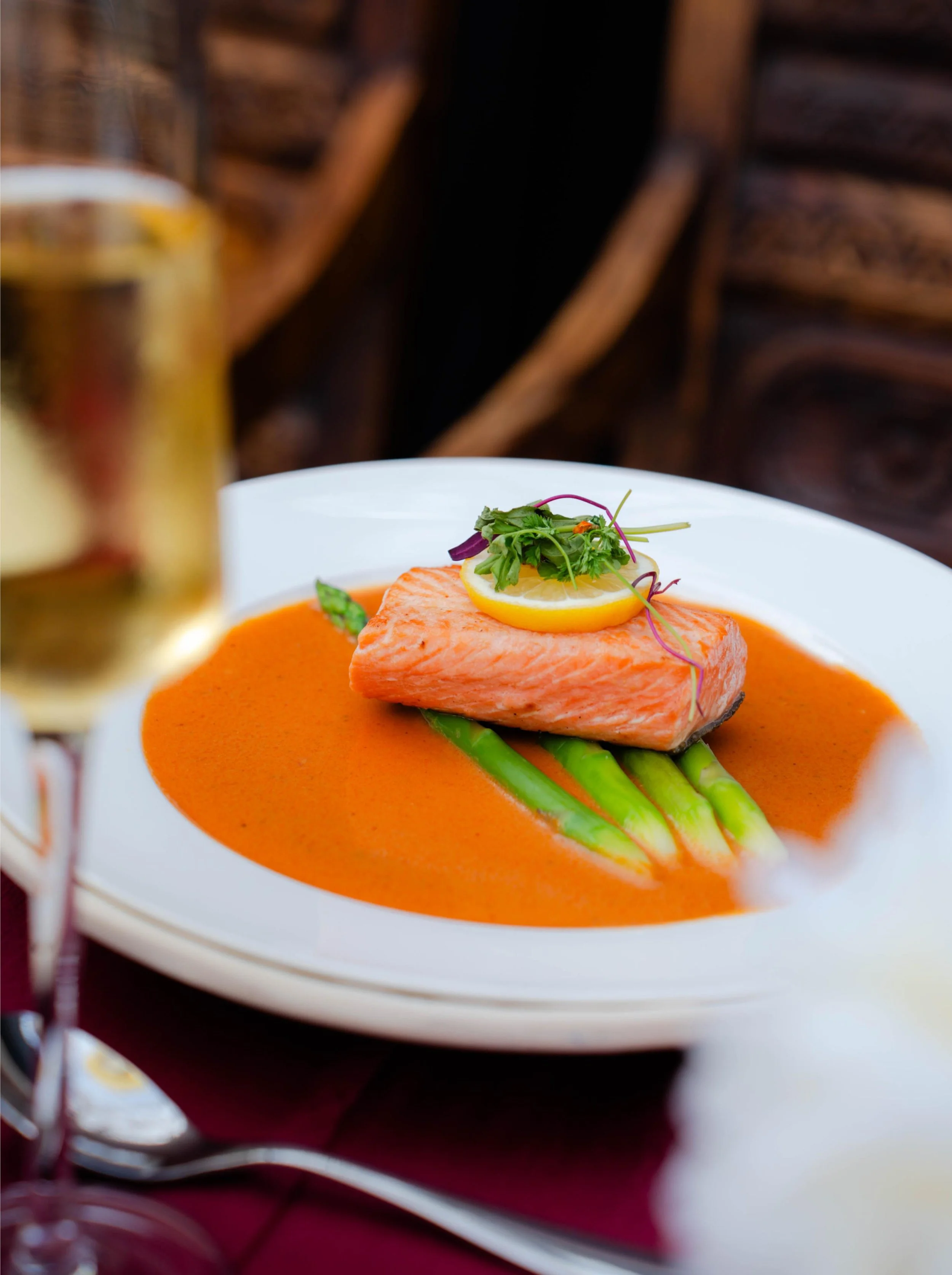 Plated salmon entrée with asparagus, citrus garnish, microgreens, and savory sauce