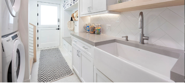 Laundry room with white cabinets, a front-loading washing machine, a zebra-patterned rug, and a large utility sink.