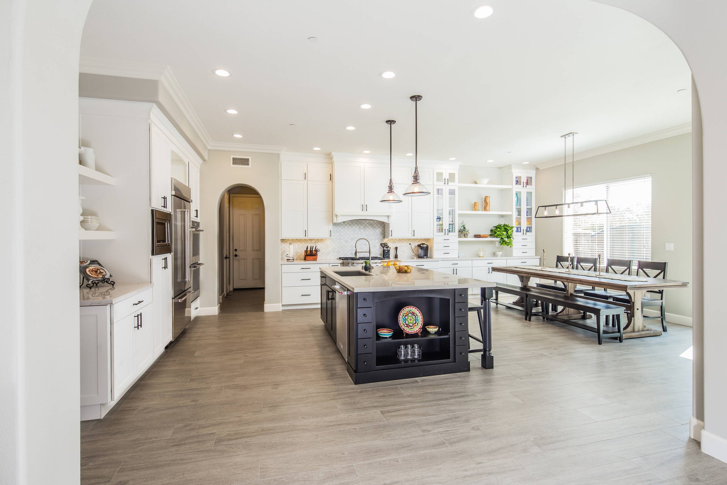 Open-concept kitchen with white cabinets, a central island, and a dining area with a long wooden table and chairs.