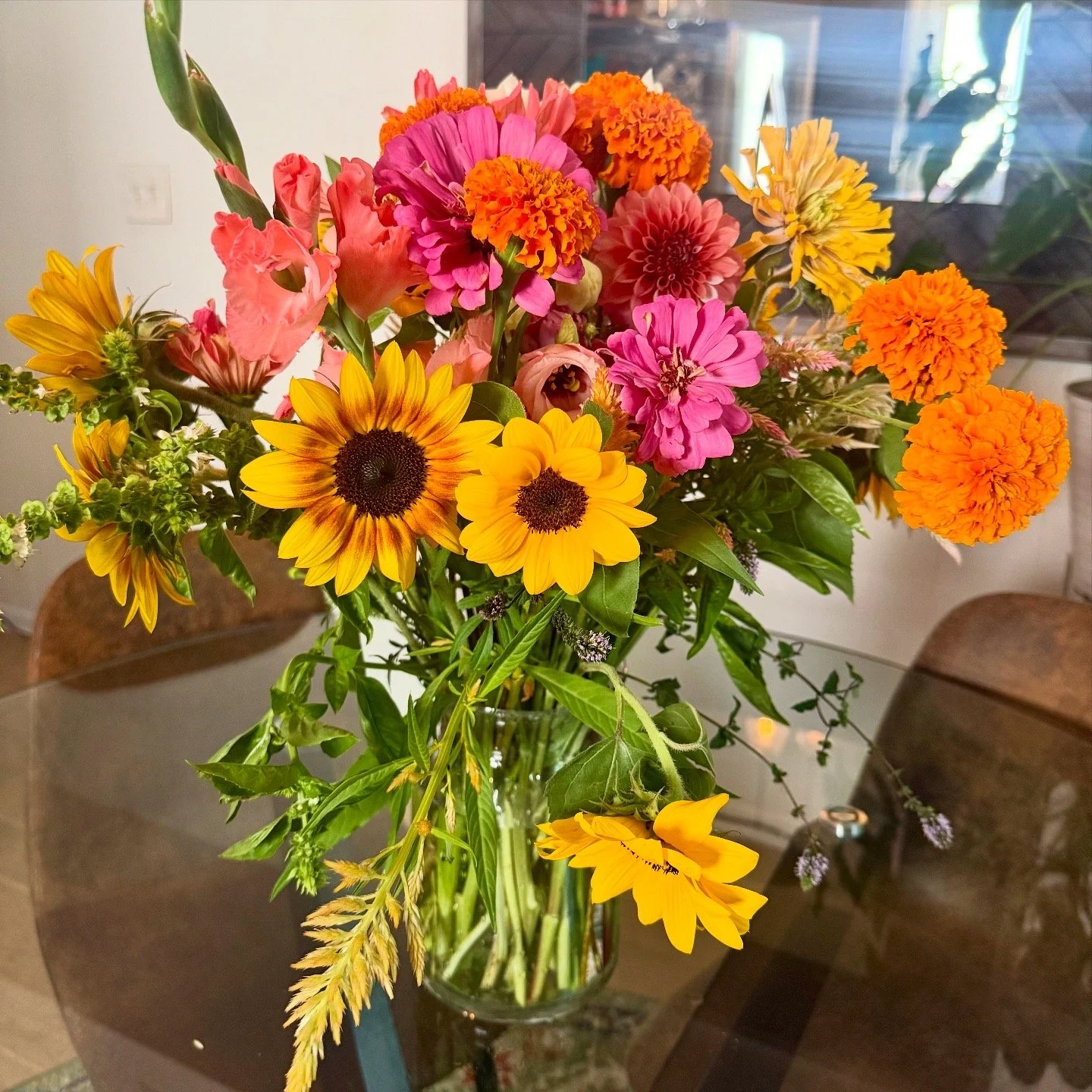 A colorful bouquet of flowers in a glass vase on a glass table.