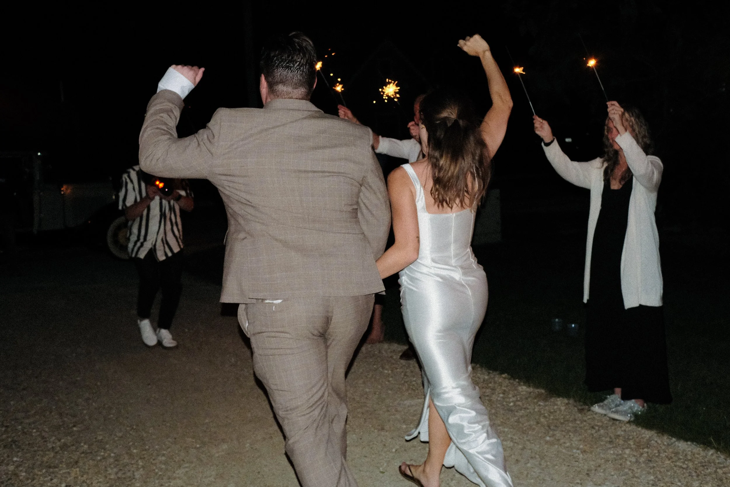 People celebrating with sparklers at night, dancing and enjoying an outdoor event.