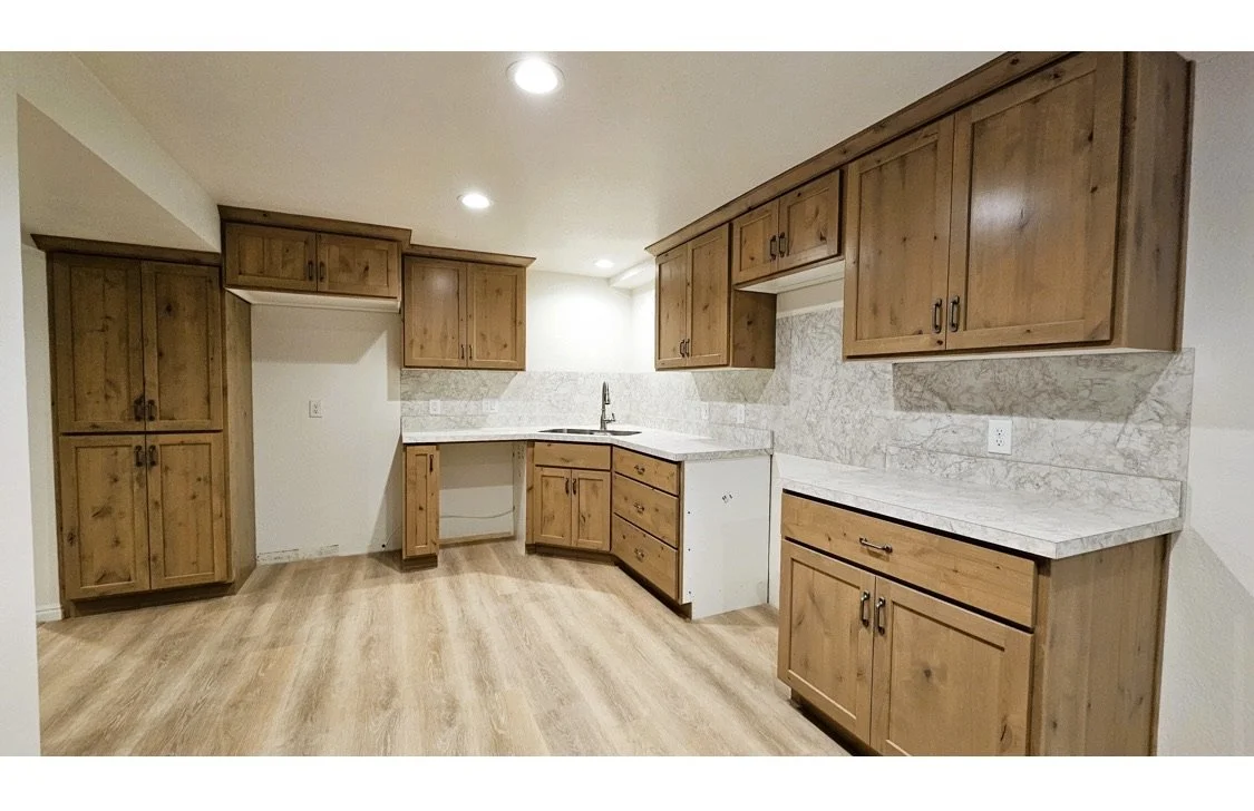 Kitchen with wooden cabinets, marble countertops, and hardwood flooring.