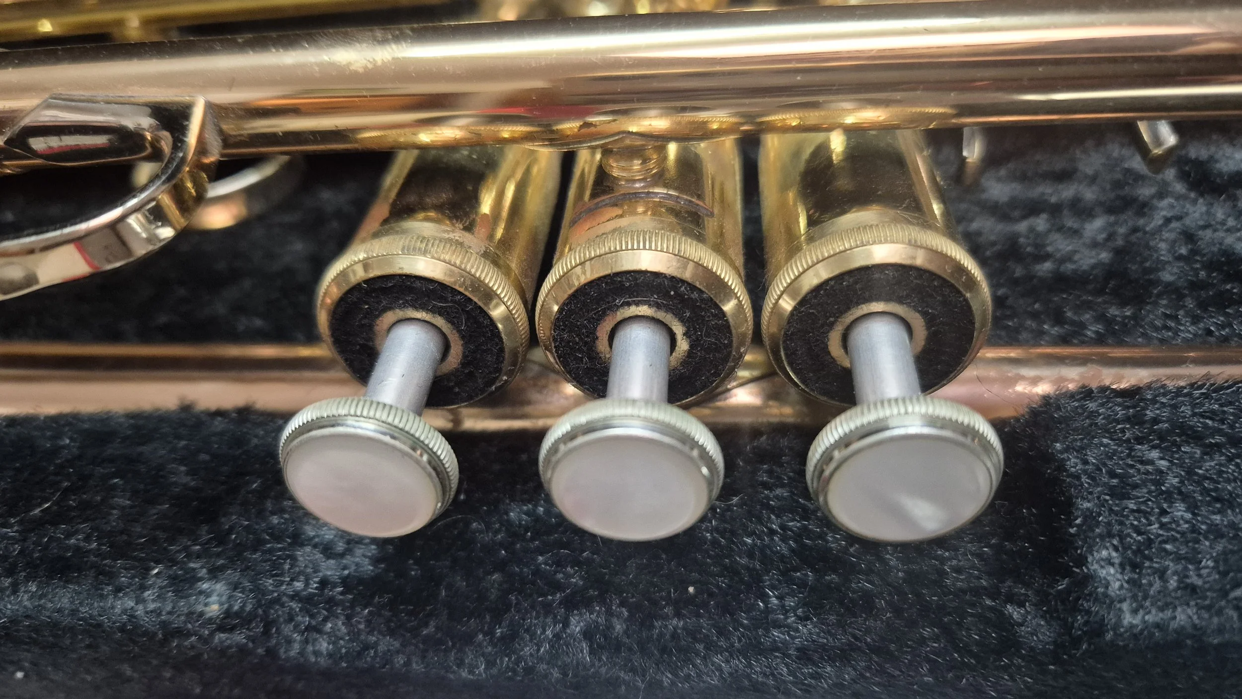 Close-up of three brass valves arranged in a row on a black surface.