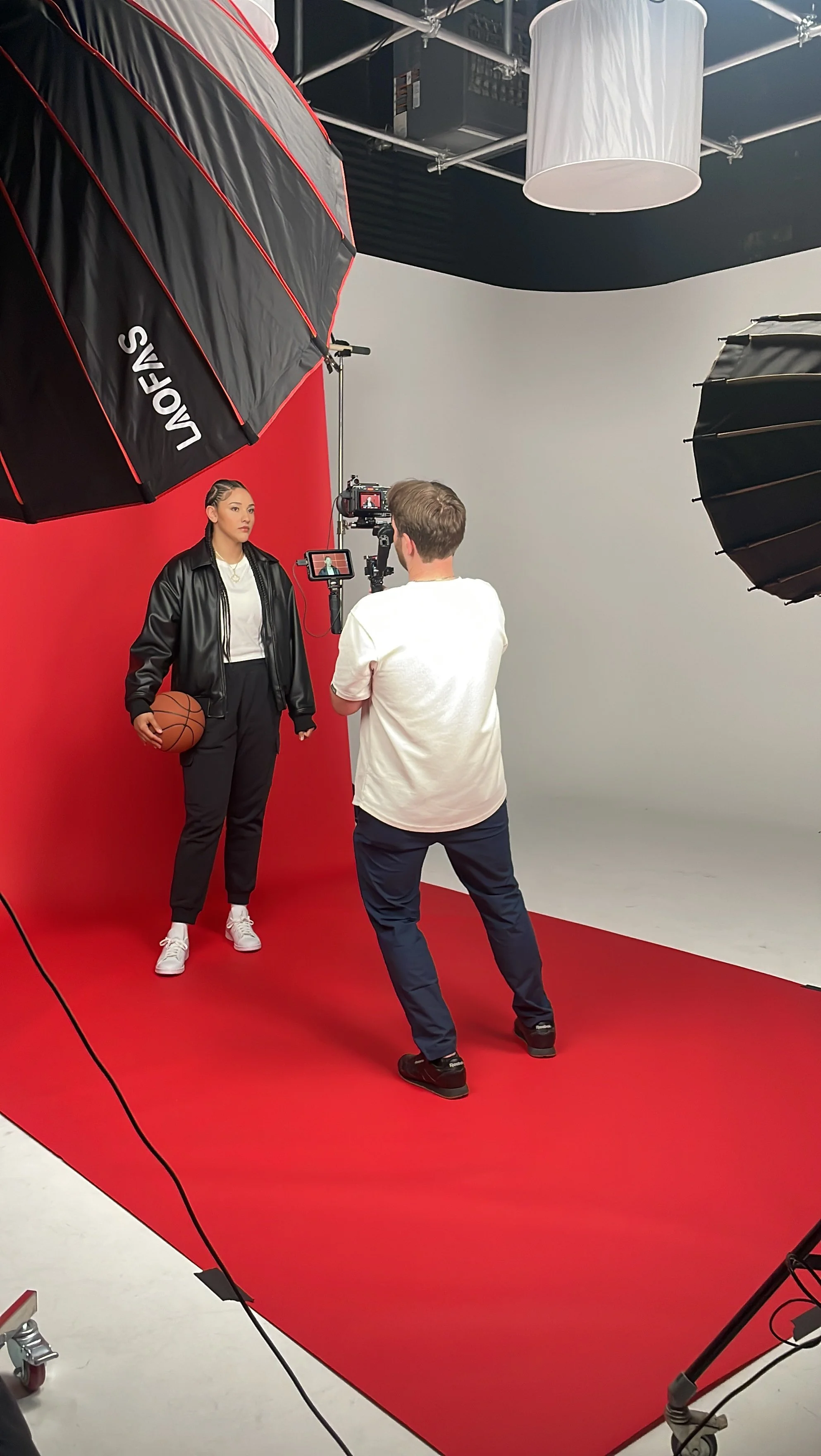 Studio video production shoot with subject on red backdrop for branded social media content
