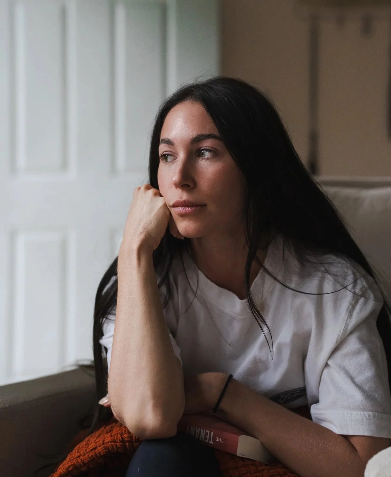 Gabriella Castellani, MS, OTR/L, in a quiet reflective moment at home, holding a book during her recovery from endometriosis excision surgery and pelvic floor physical therapy.