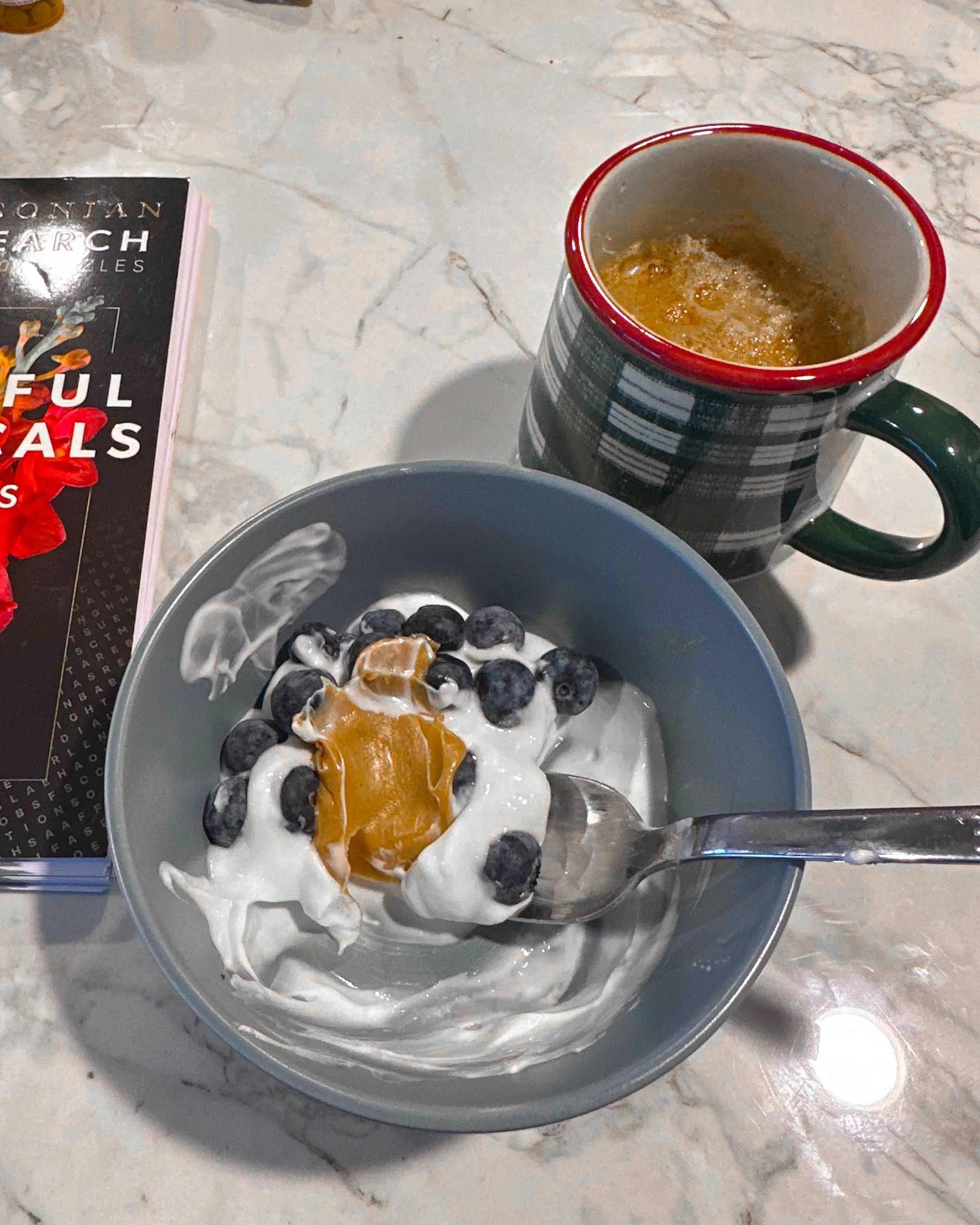 Yogurt with blueberries and peanut butter beside tea as part of a gentle endometriosis recovery routine.