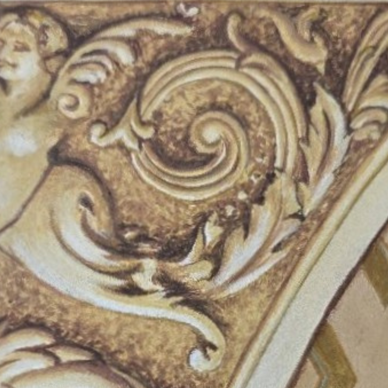 Close-up of an ornate, carved wood or plaster decoration featuring a spiral pattern and swirling floral motifs with a gold or bronze finish.