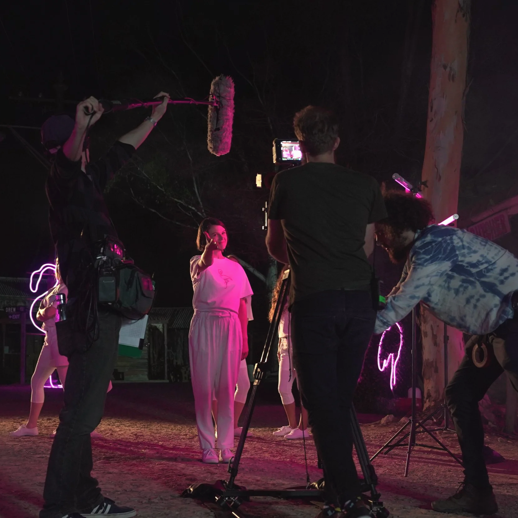 Behind-the-scenes film crew shooting award-winning web series Dead Centre, directed by Benno Thiel. Alistair Schmidt records location sound, with pink neon lighting highlighting creative cinematography.