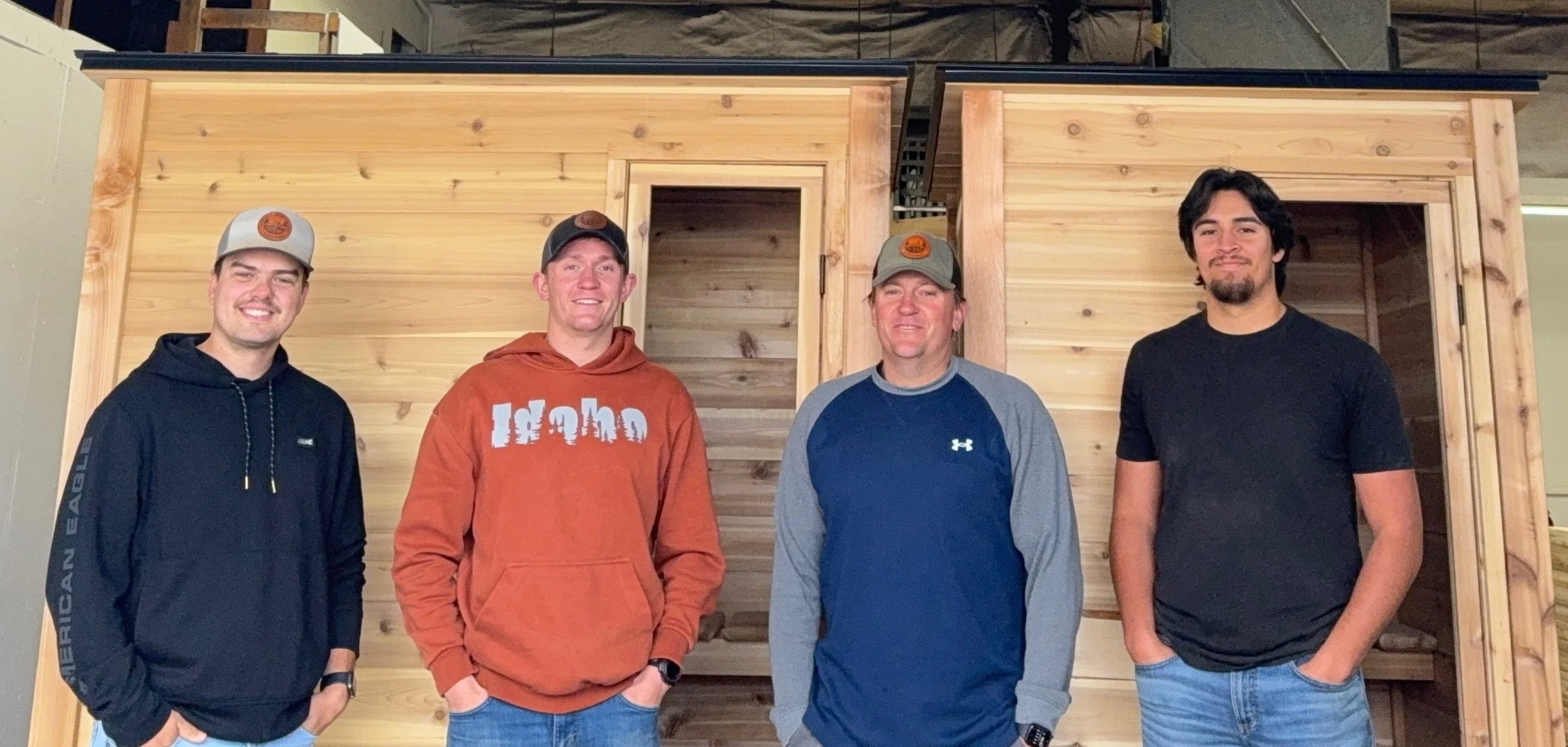 Four men standing side by side inside a wooden structure.