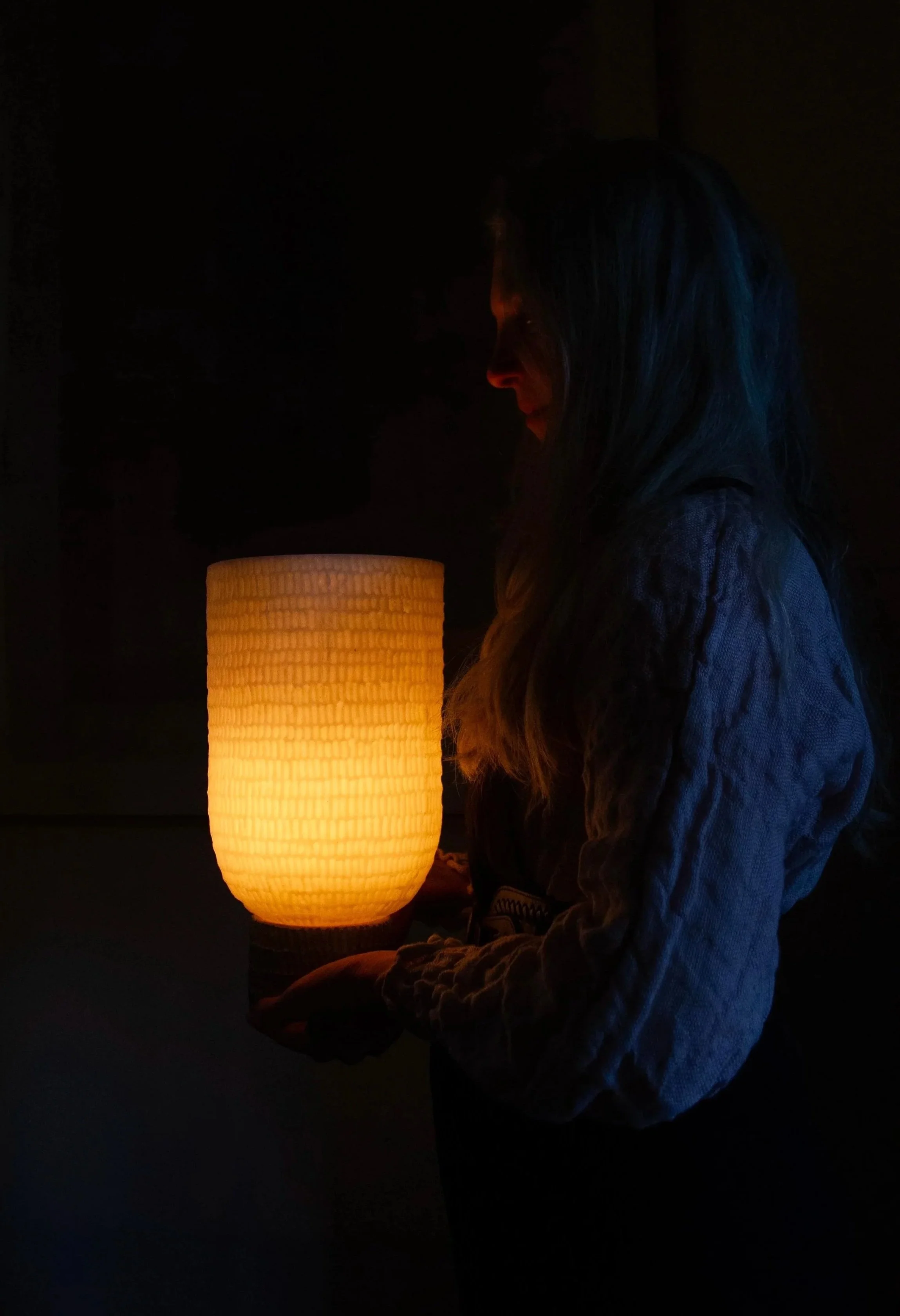 glowing wax lantern being gently held and gazed down on by woman
