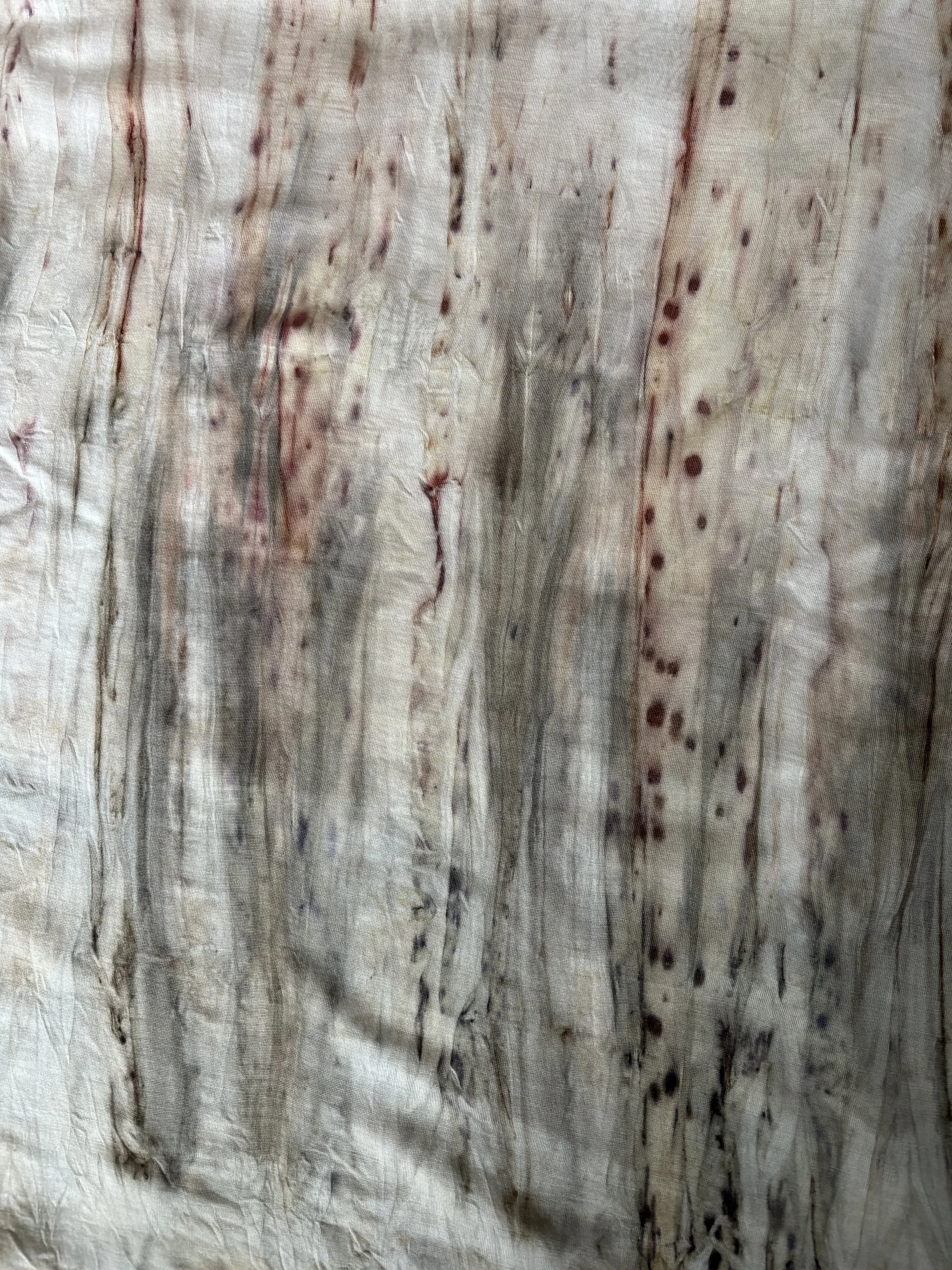 Close-up of a textured surface with natural wood grain and reddish-brown streaks and dots.