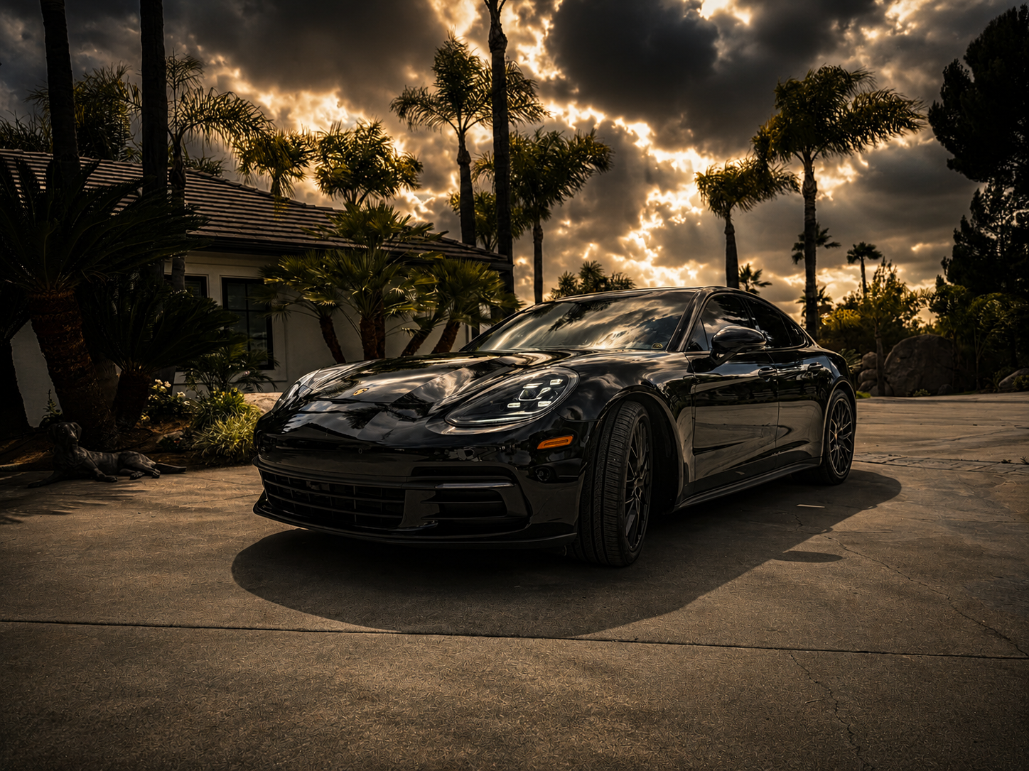 Detailed Black Porsche Panamera with mirror-like paint reflections at golden hour showcasing Santo's Suds premium detailing results