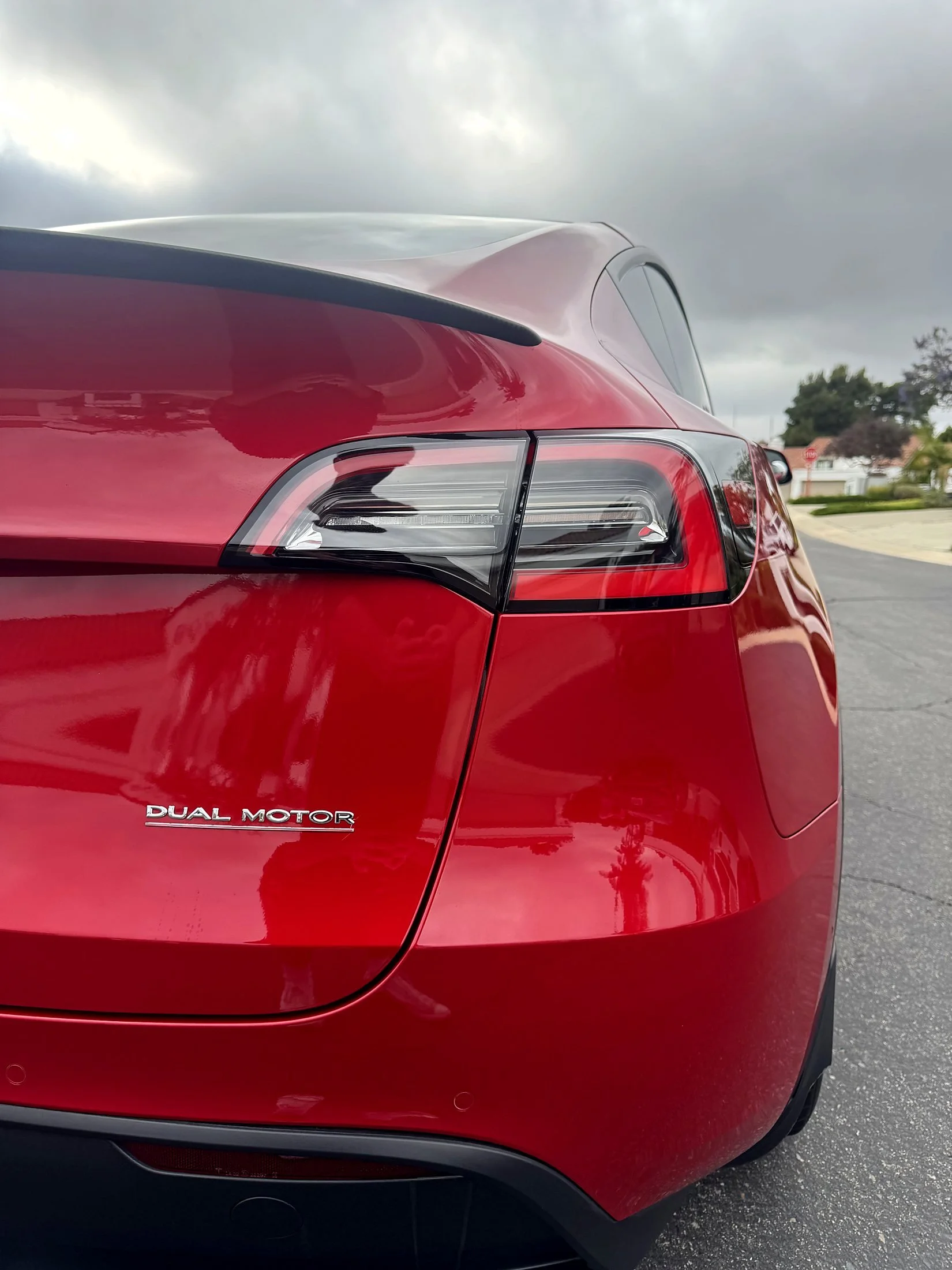 Rear taillight and glossy red paint on a Tesla Model X after an exterior detail