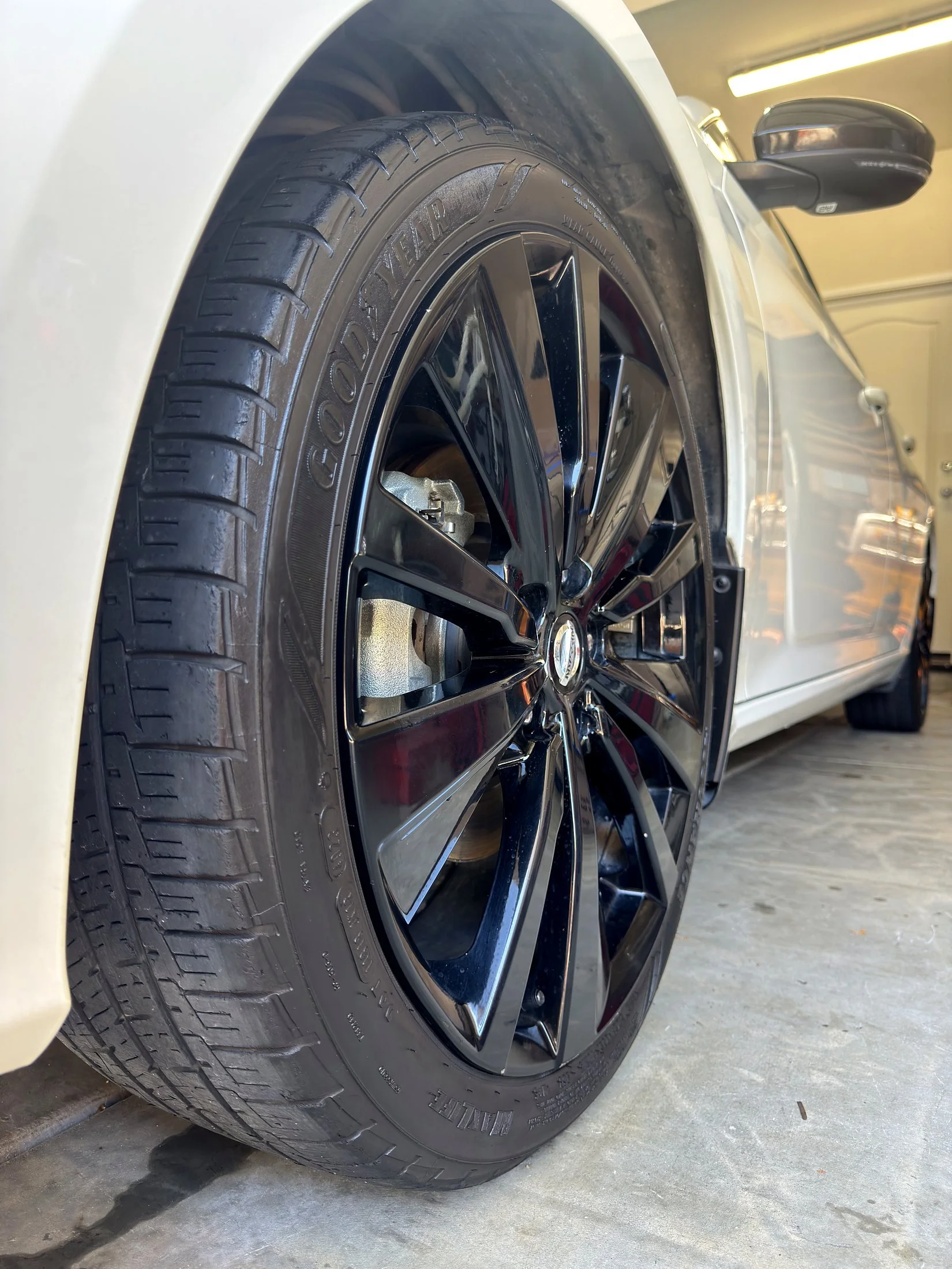Gloss black wheel with tire shine on a white Nissan Altima