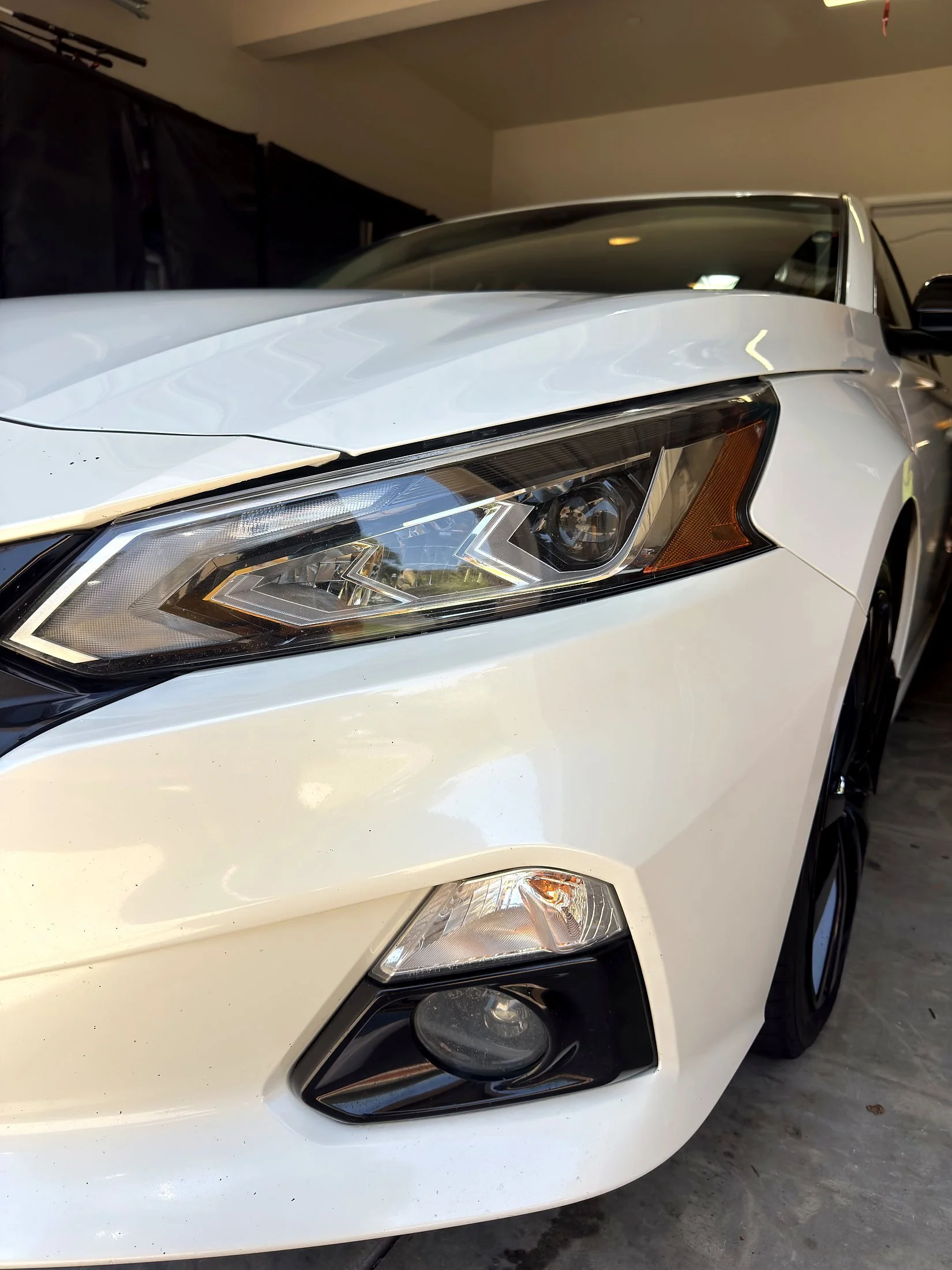 Clear headlight and clean white paint on a Nissan Altima