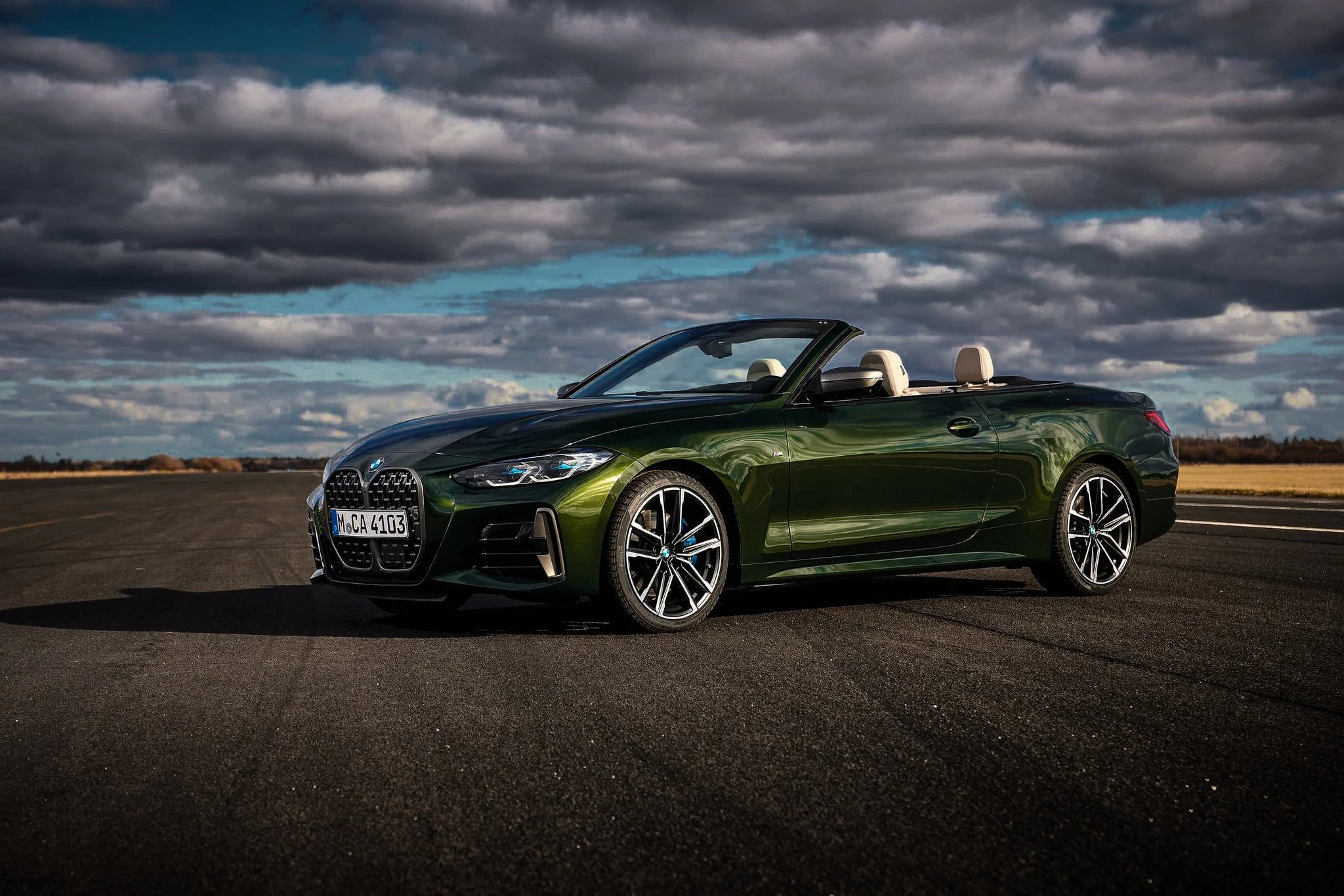 Green BMW M440i side profile with freshly detailed paint and wheels against a dramatic cloudy sky