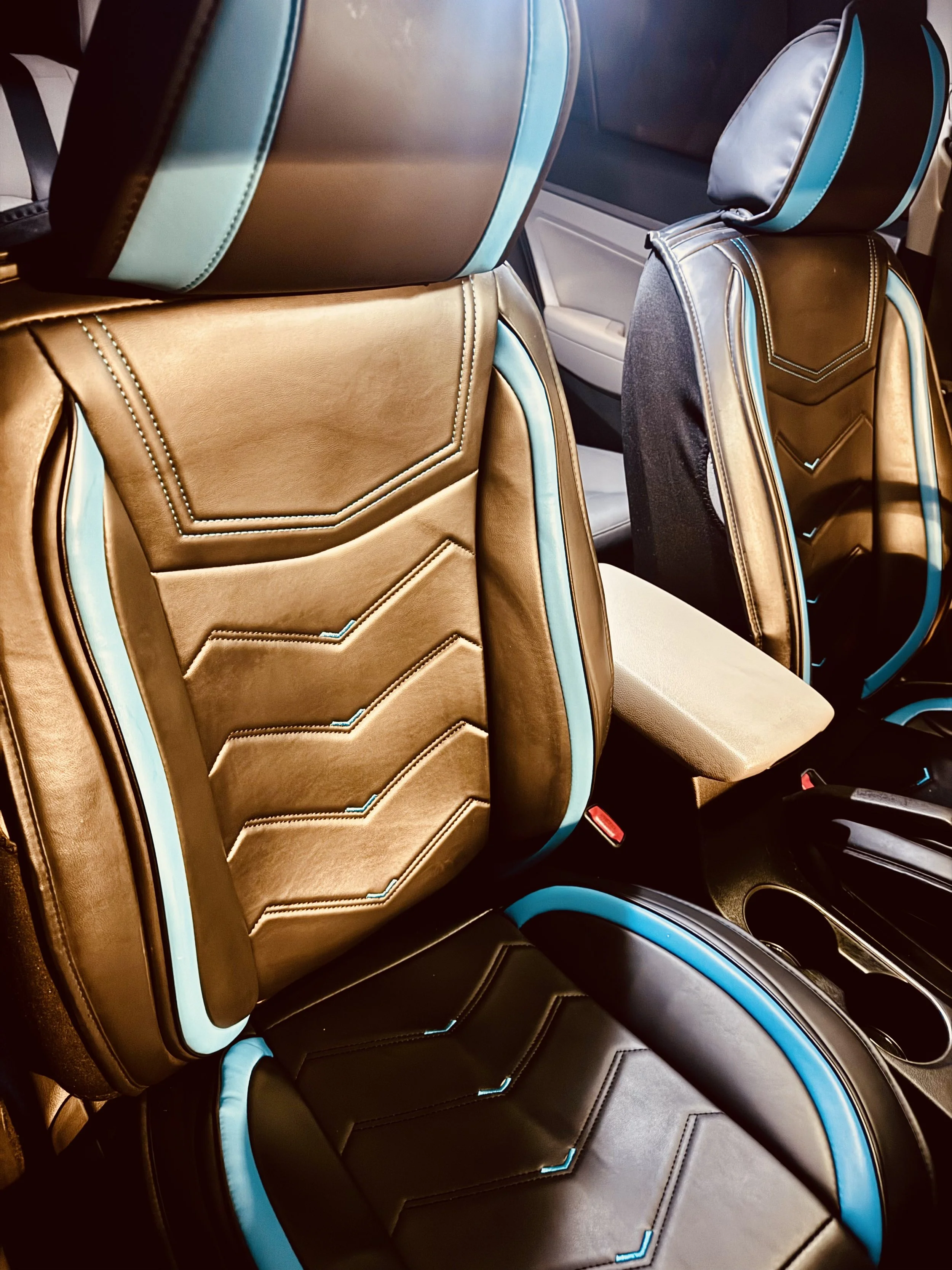 Front seats of a car with gold and black upholstery accented with blue piping.
