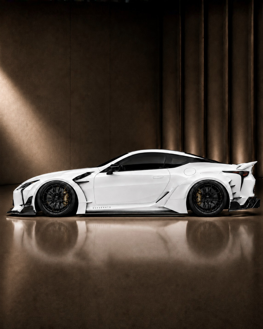 A Lexus LC 500 Esagerato with black wheels and tinted windows displayed indoors against a dark brown background.