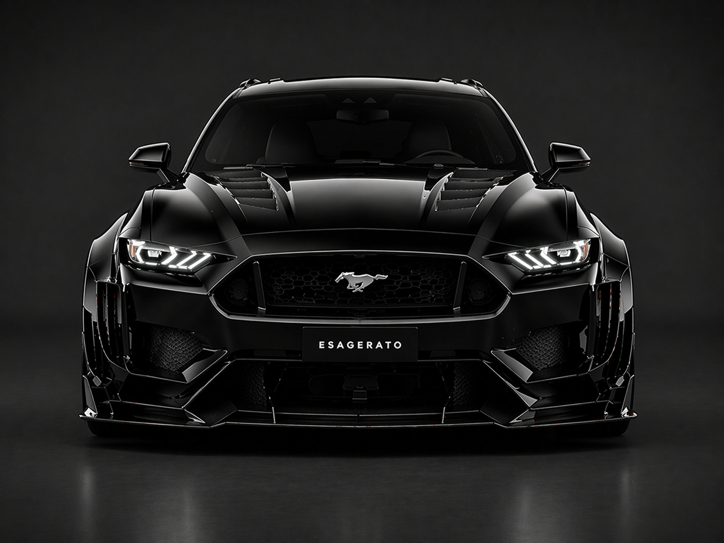 Front view of a black Ford Mustang Shelby GT Esagerato car with aggressive styling, LED headlights, and a prominent grille, set against a dark background.