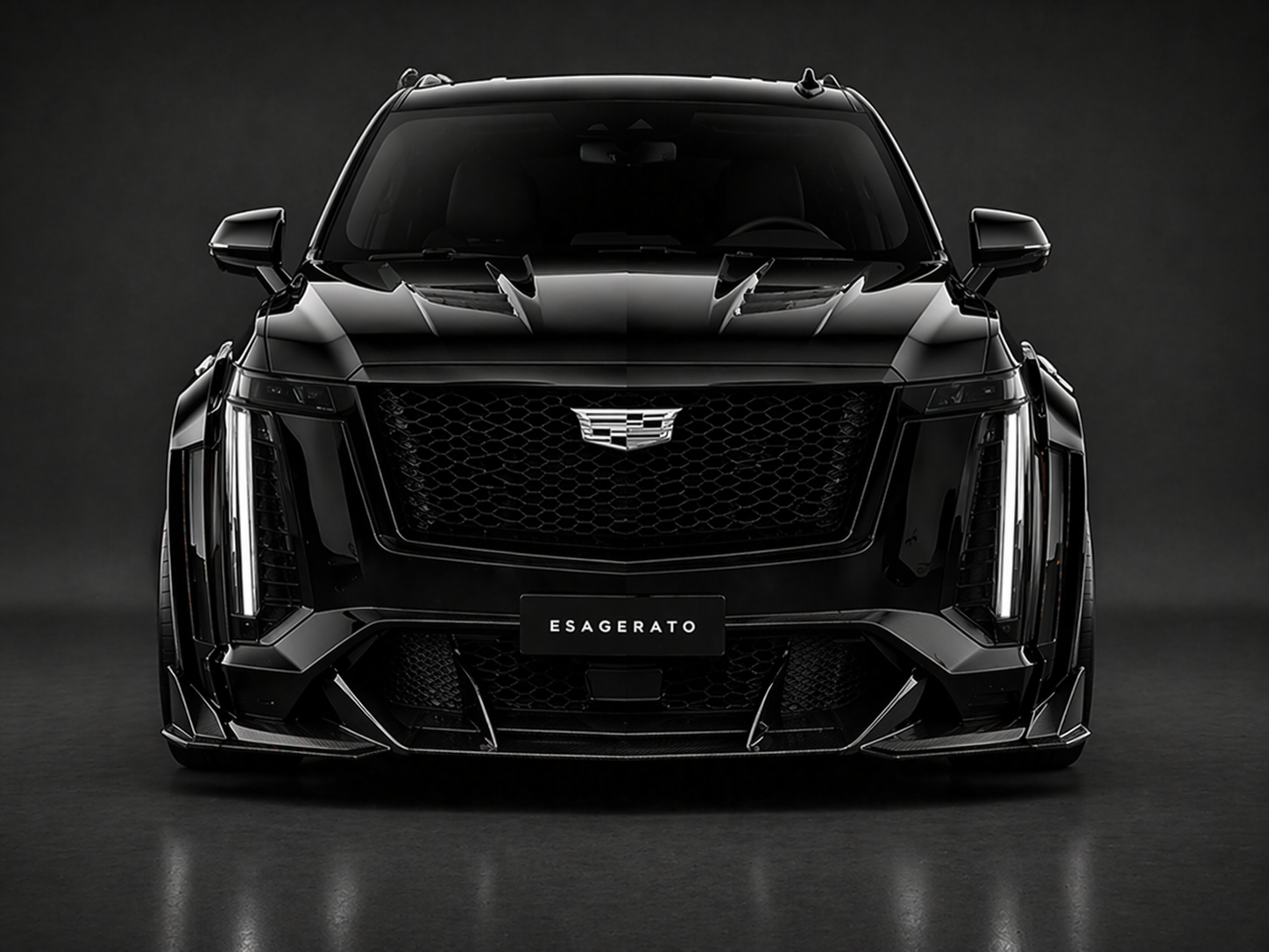 Black Cadillac Escalade vehicle front view with a sleek and modern design, prominent grille, and headlights. It features a license plate that reads 'ESAGERATO' and is set against a dark background.