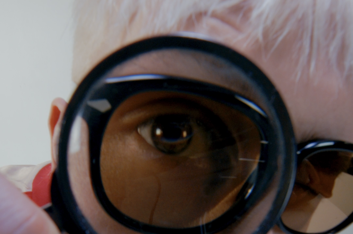 Close-up of a person looking through a magnifying glass, revealing only one eye.